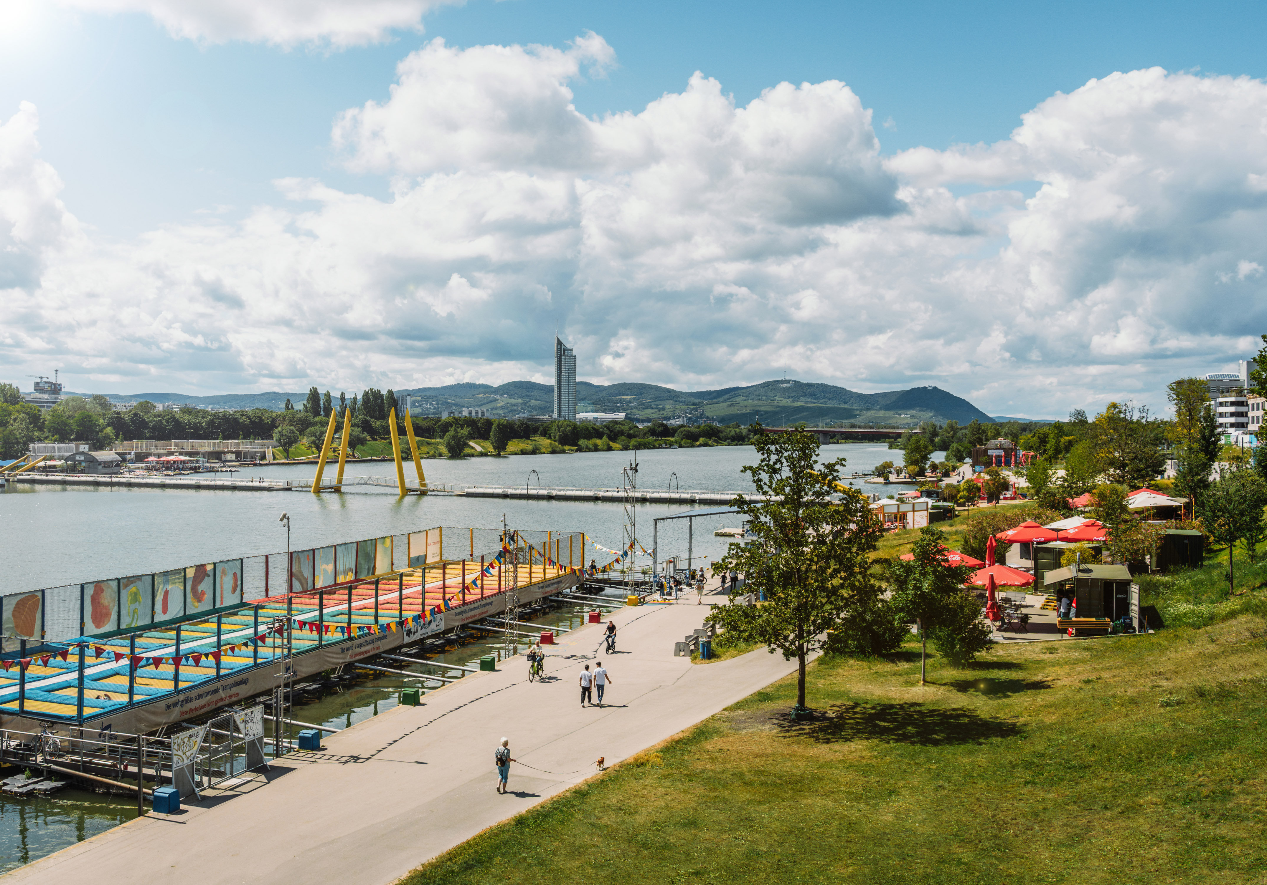 Vienna's Danube Island waterfront with a floating trampoline park and city skyline.