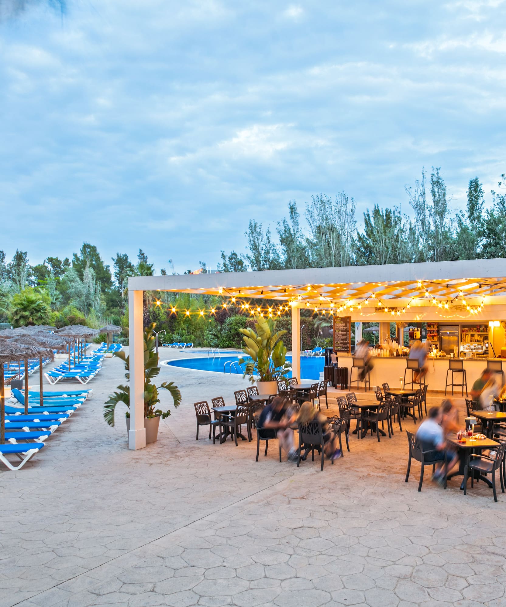 a group of people sitting at tables and chairs in a pool