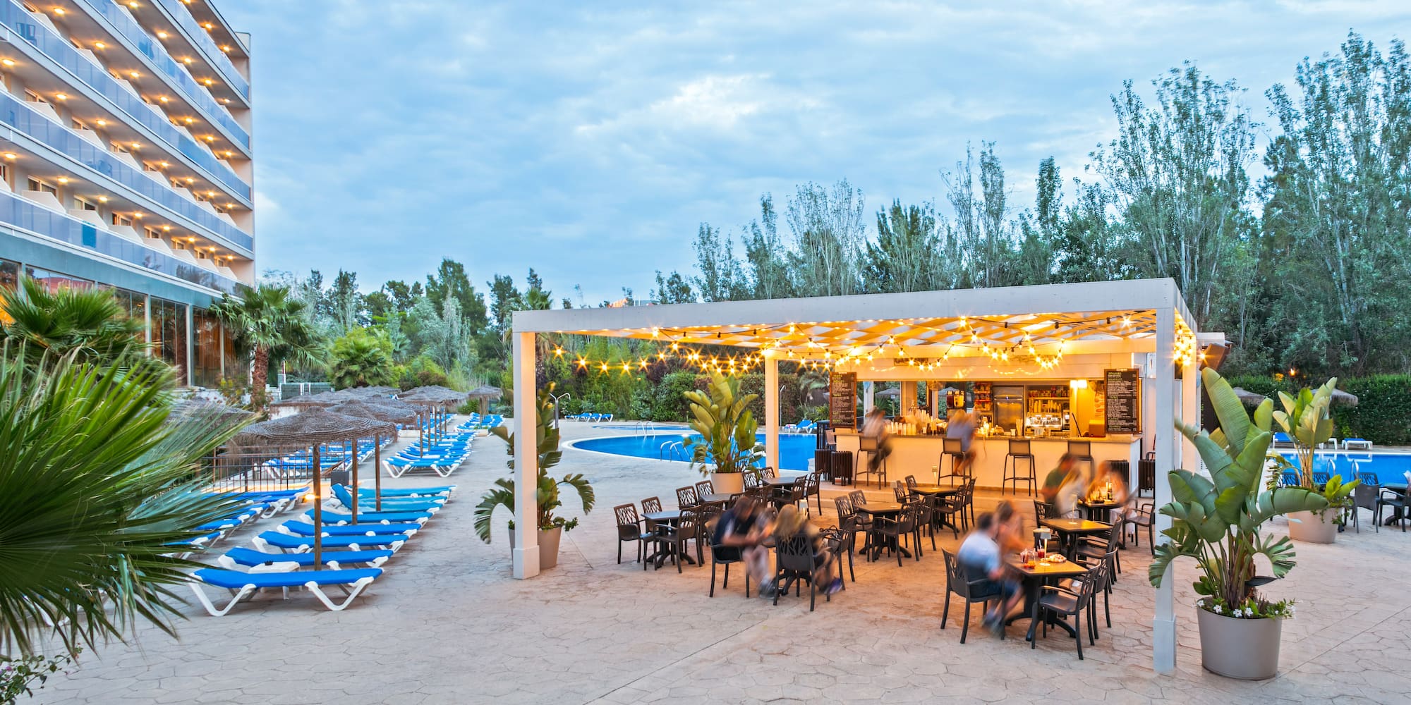 a group of people sitting at tables and chairs in a pool