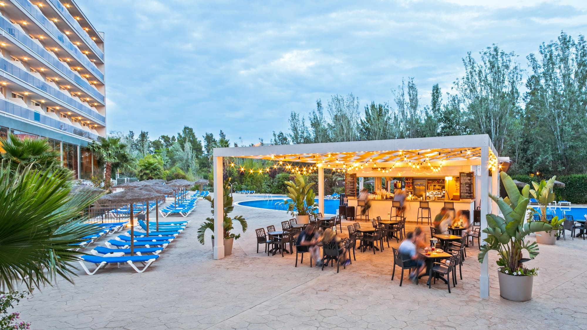 a group of people sitting at tables and chairs in a pool