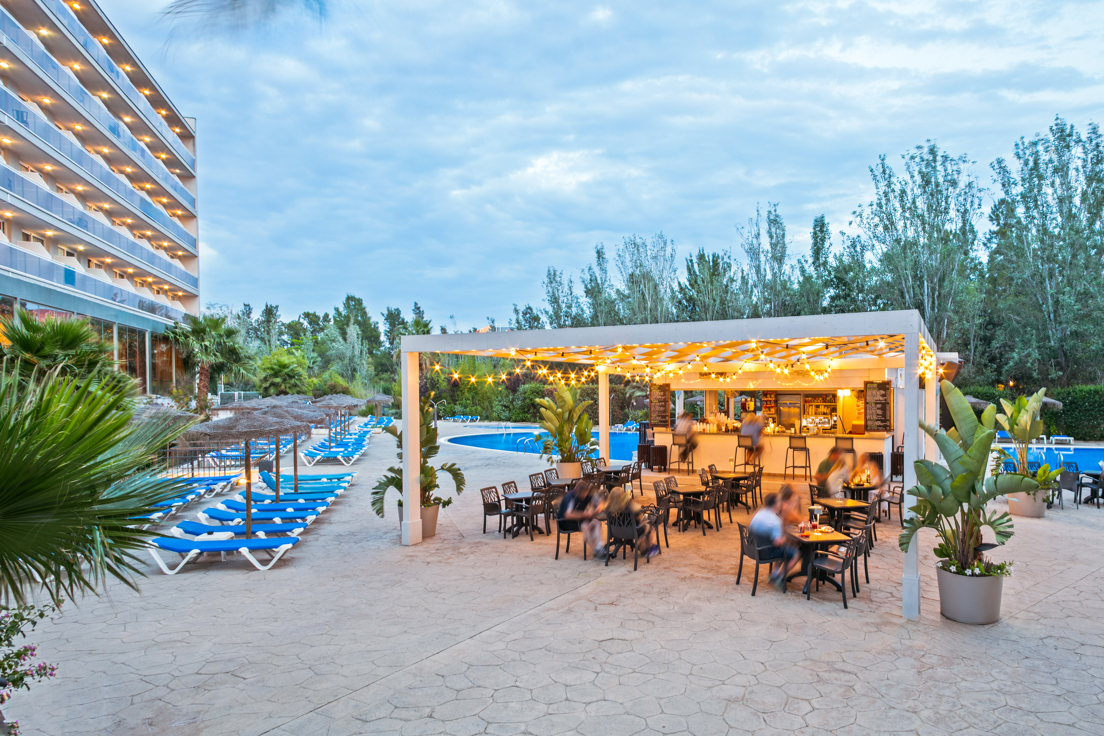 a group of people sitting at tables and chairs in a pool