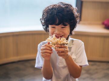 a boy holding a small container of food