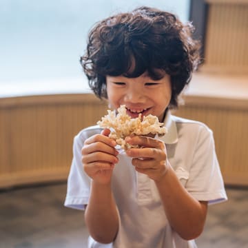 a boy holding a small container of food