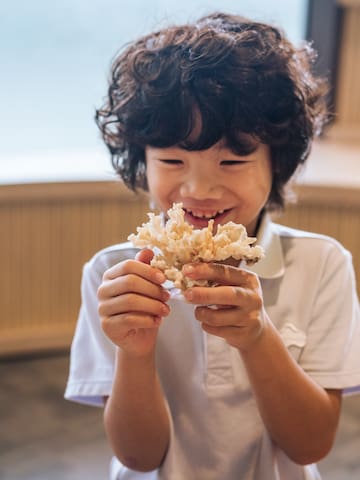 a boy holding a small container of food