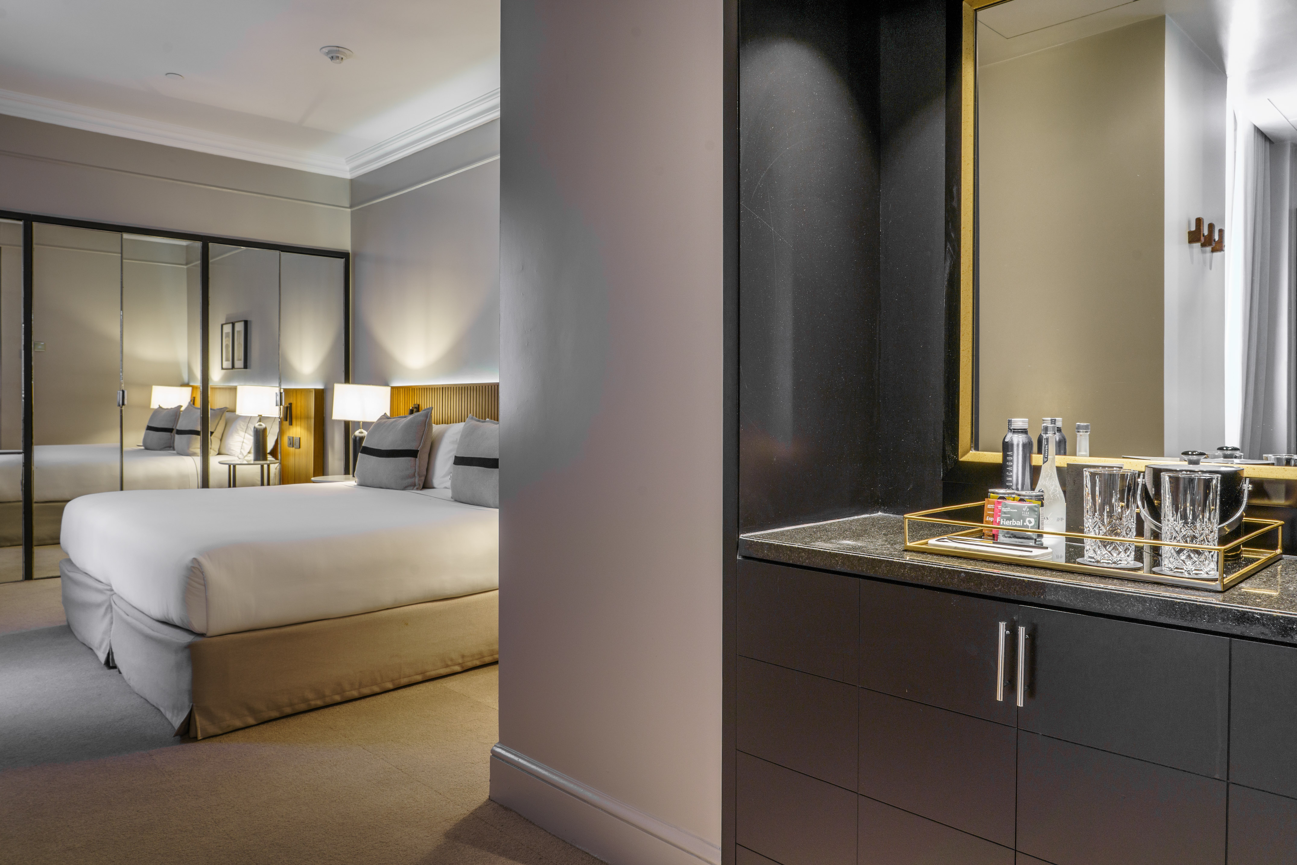 Luxurious hotel bedroom with king bed, elegant decor, and well-stocked mini-bar.