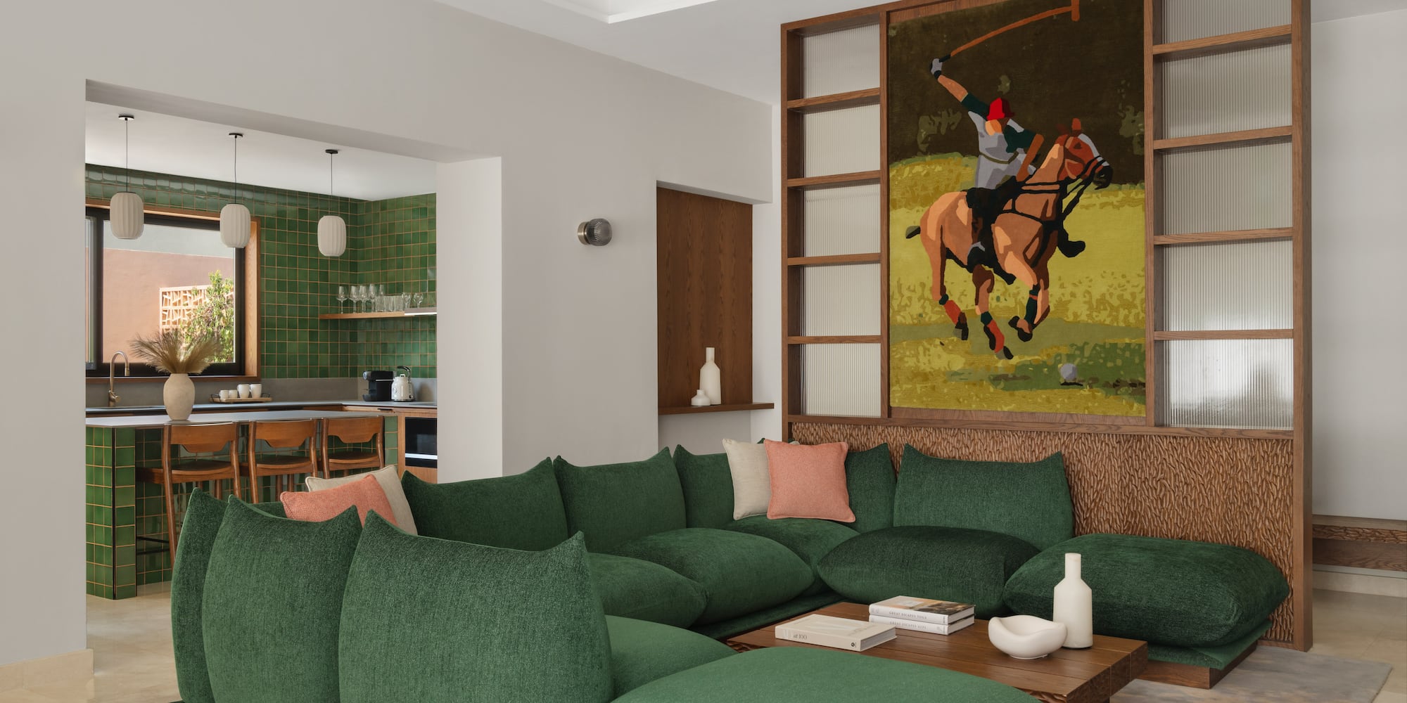 a living room with a large green couch and a painting of a polo player