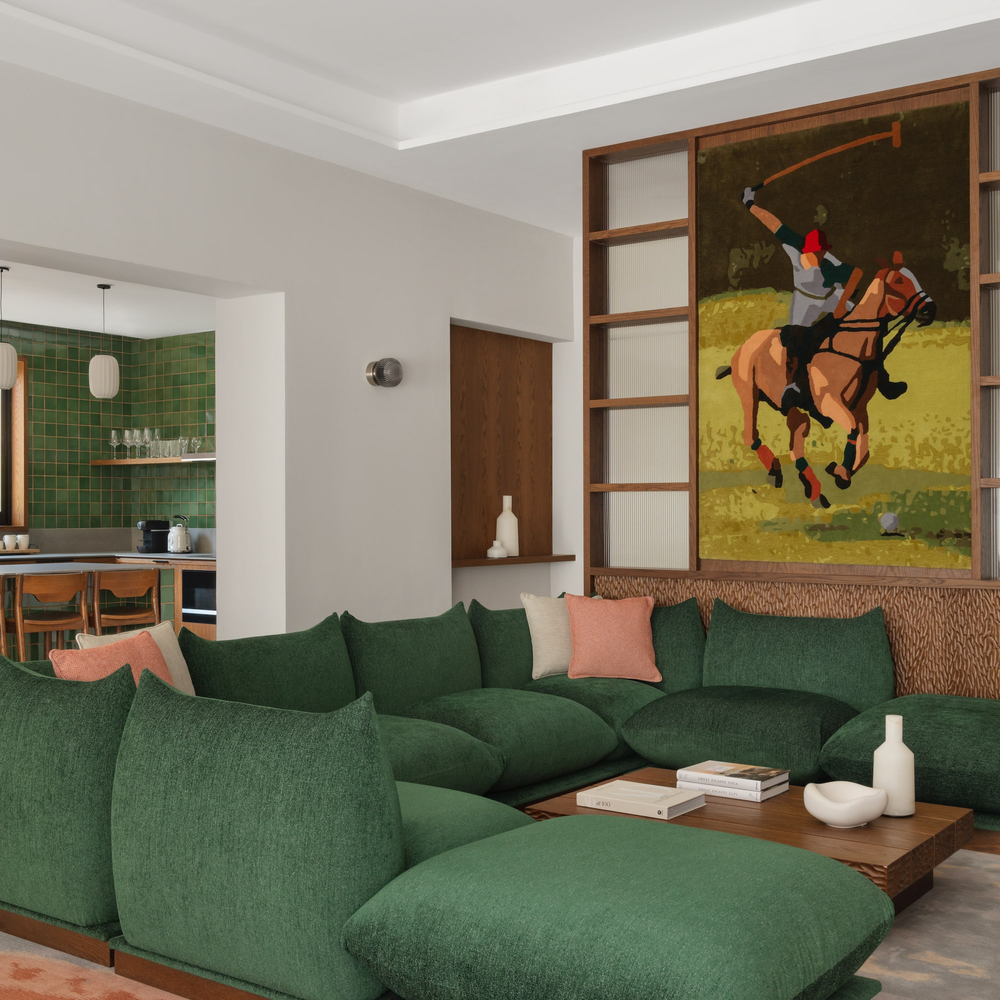 a living room with a large green couch and a painting of a polo player