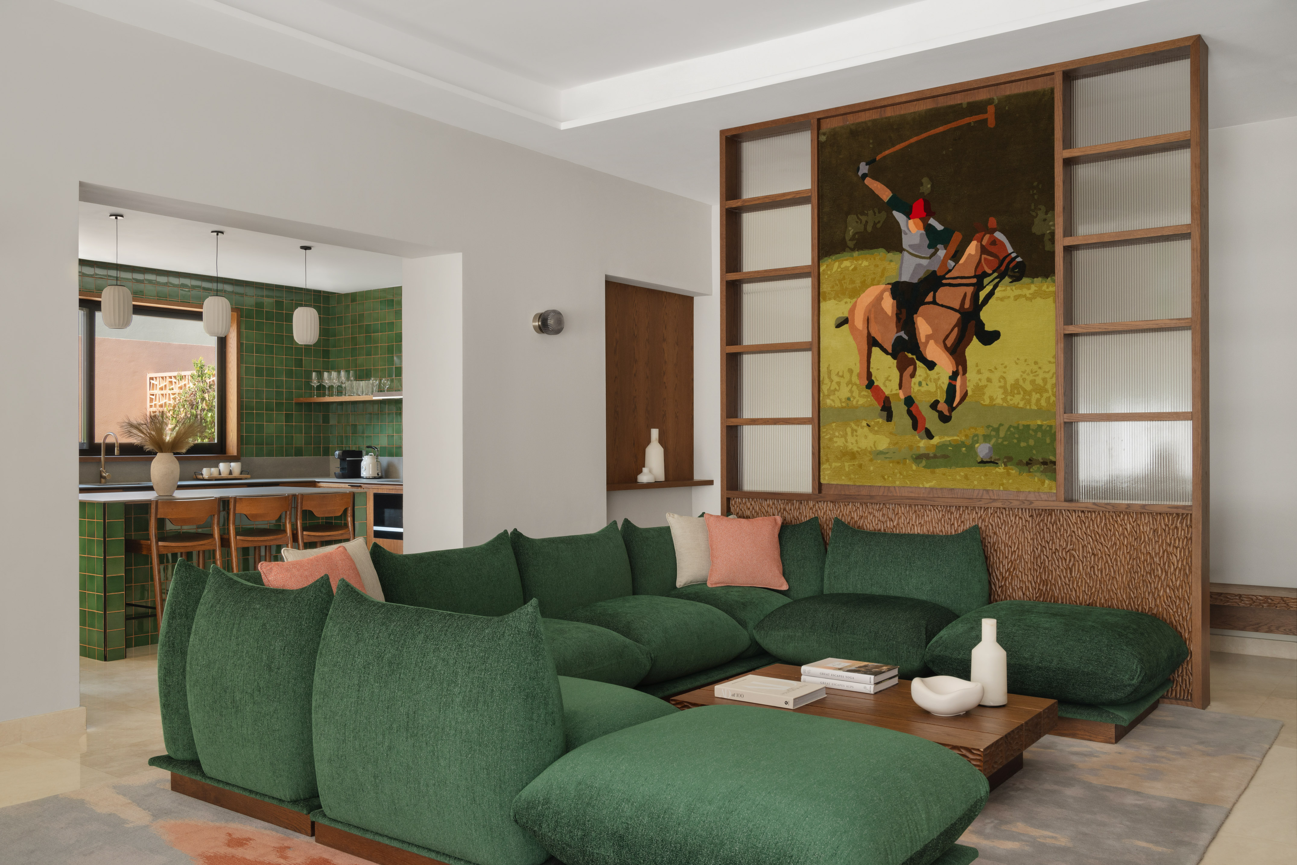 Green sofa living room with polo art, wooden divider, and modern tiled kitchen.