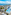 Tropical beachfront resort with large pool, palm trees, and ocean view.