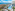 Aerial view of beachfront resort with large pool, palm trees, and ocean.