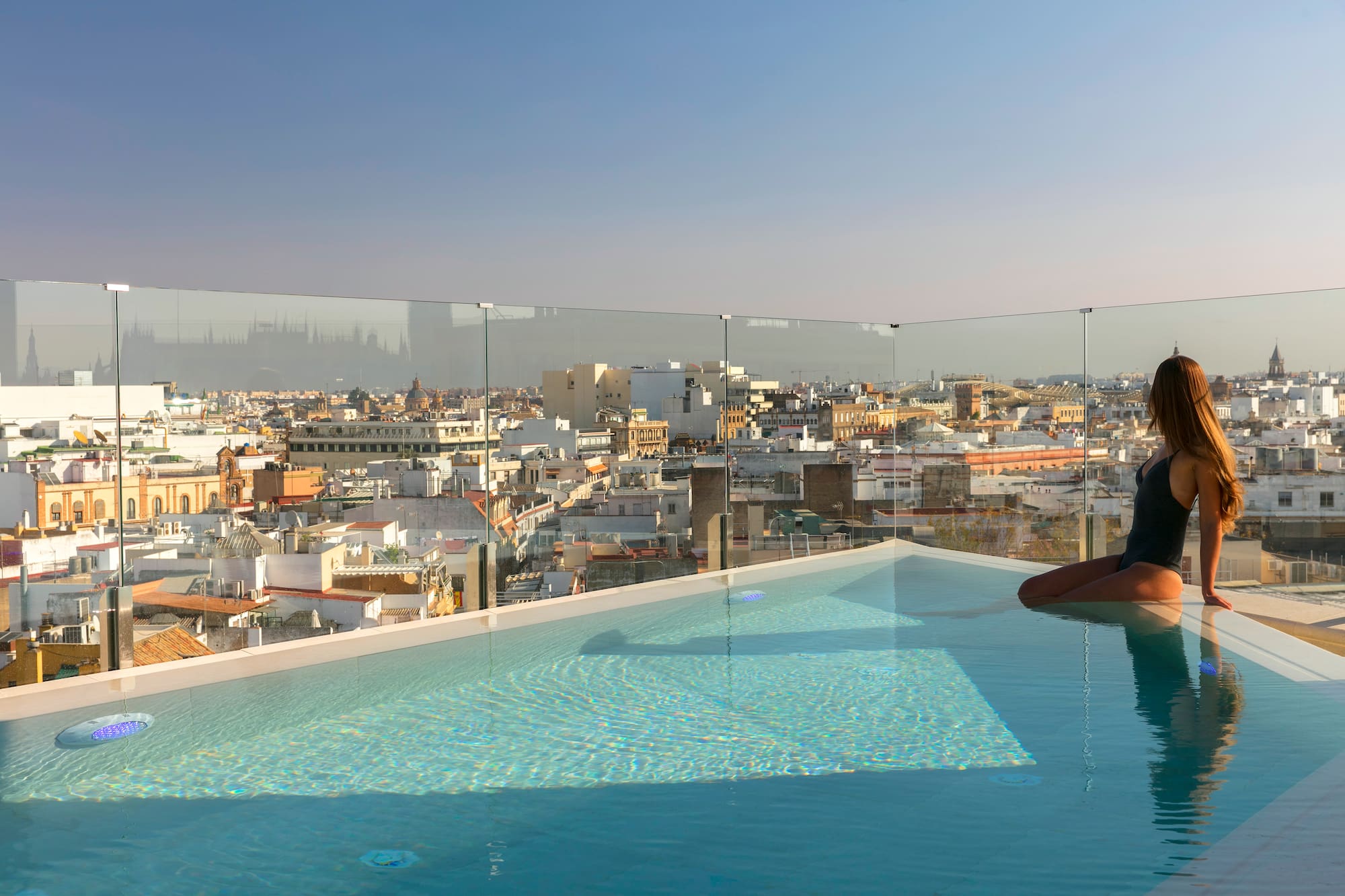 Mujer en piscina de azotea con vistas a la ciudad de Sevilla.