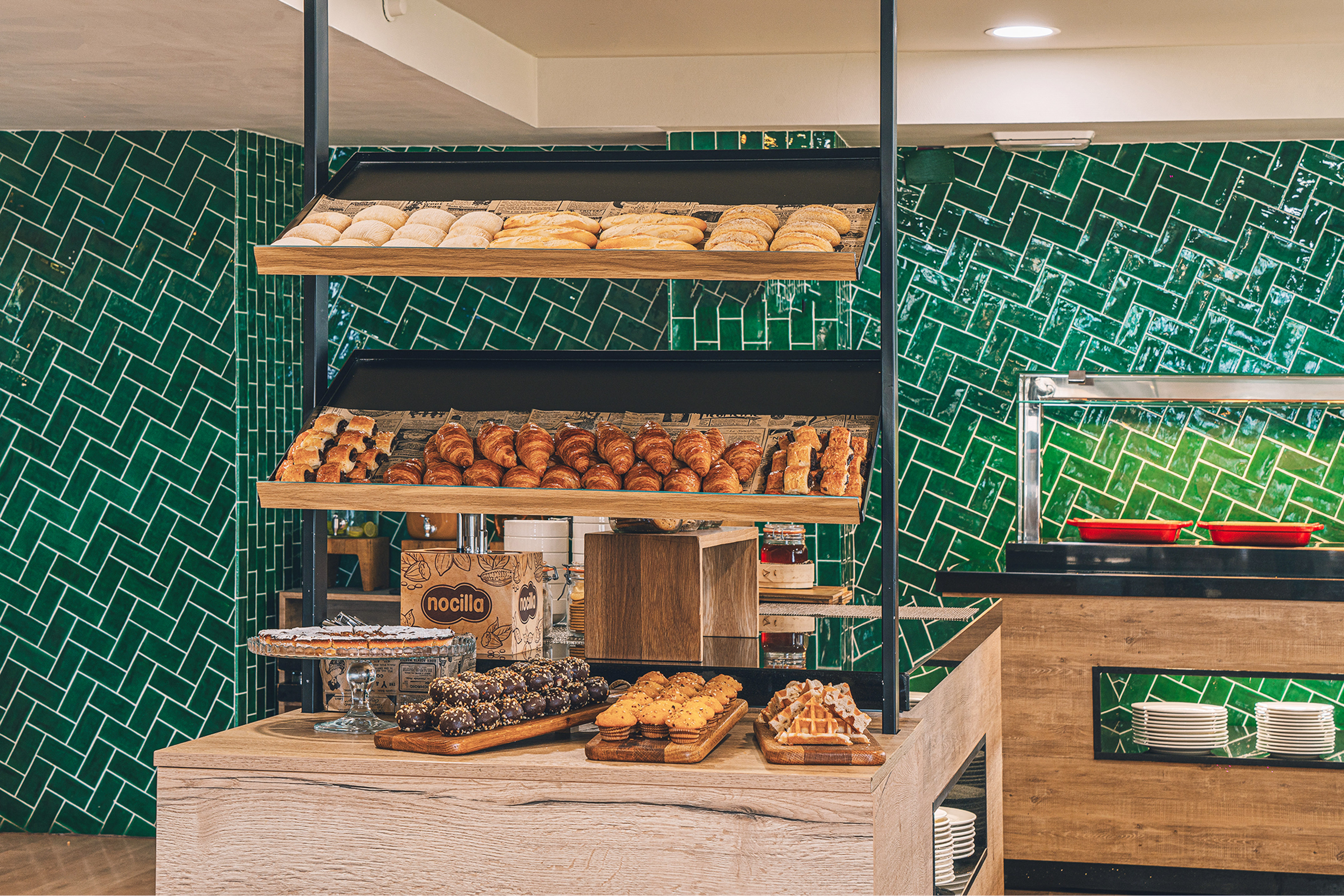 Hotel breakfast buffet with fresh croissants, bread, pastries, and desserts.
