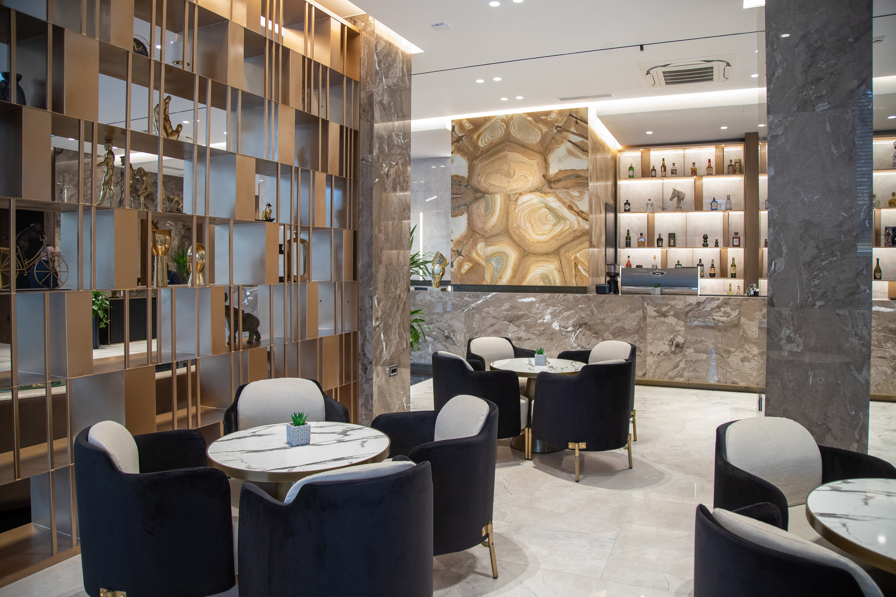 Modern hotel lounge with black velvet chairs, marble tables, and stylish bar.