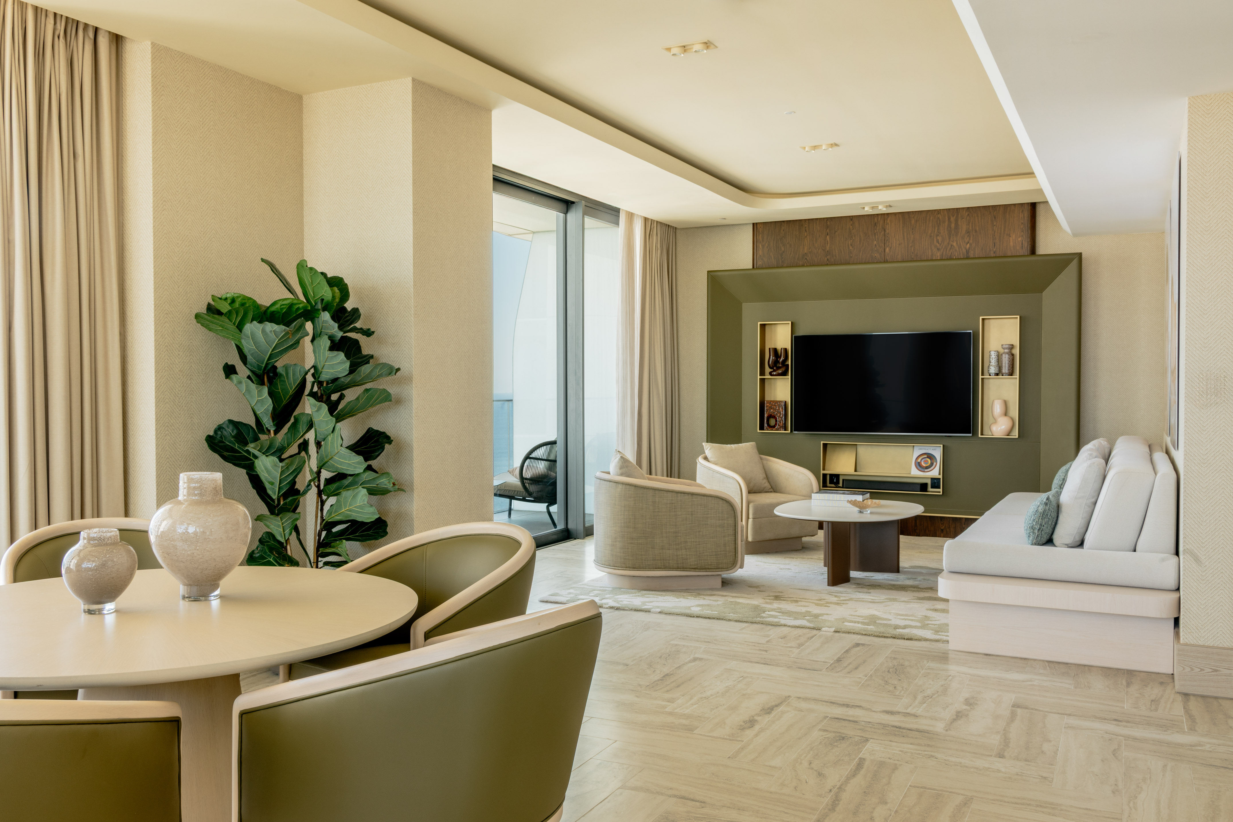 Luxury hotel suite: olive green living room, dining area, sea view.