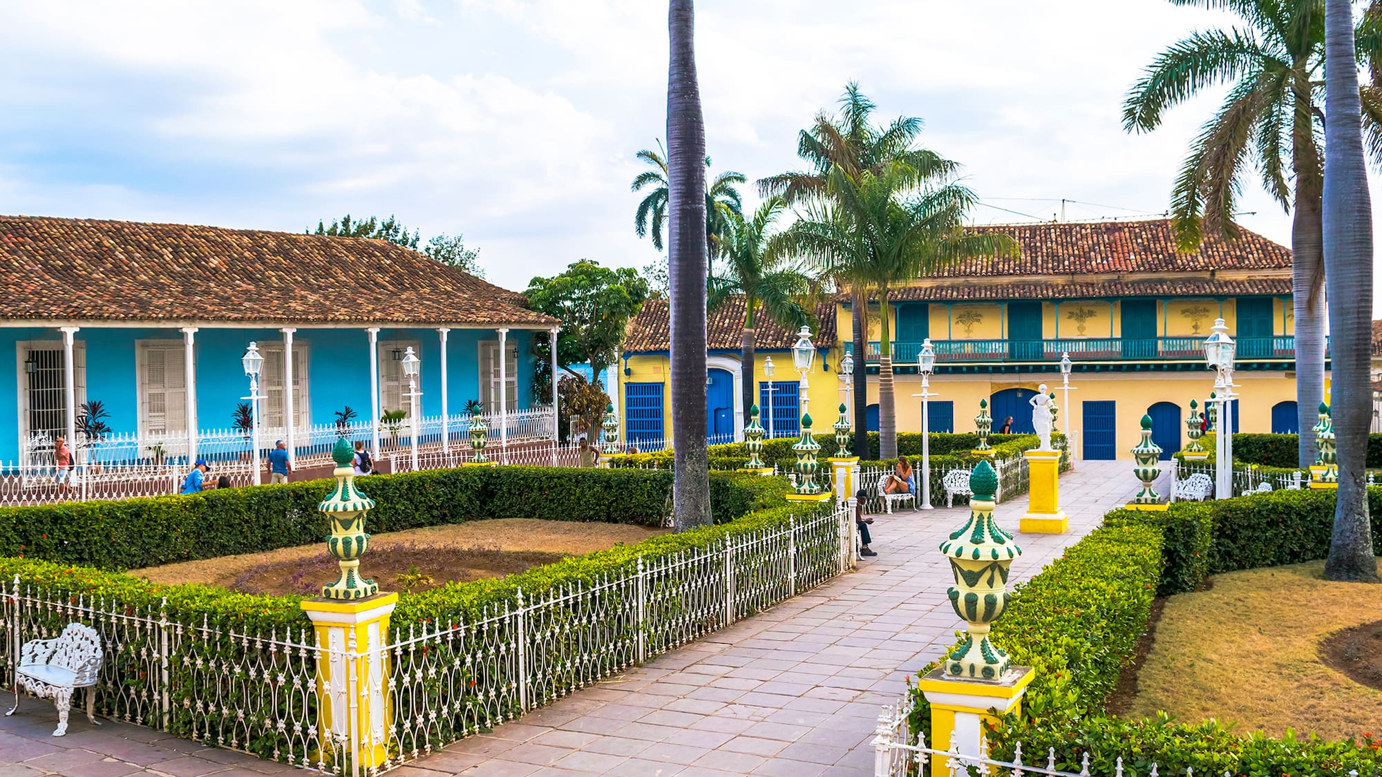 a walkway with bushes and trees in front of a building