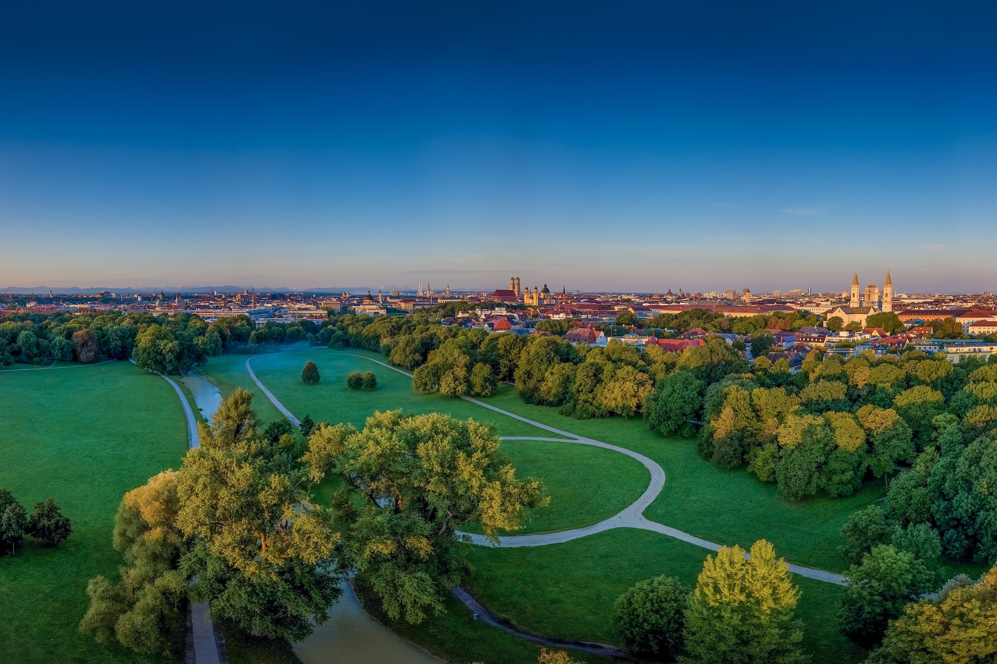 Vista aérea de Múnich al atardecer, con Jardín Inglés y catedrales.