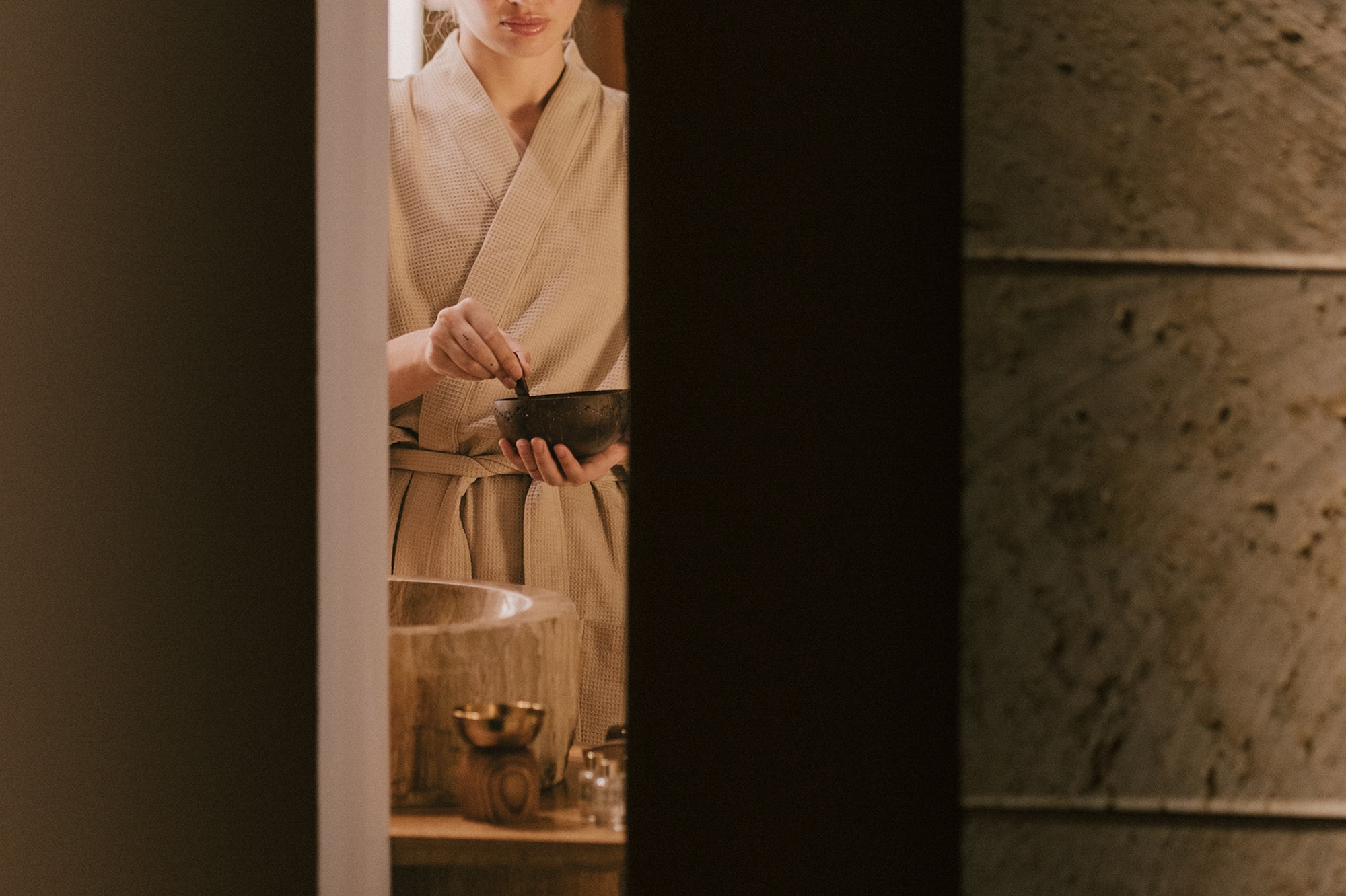 Mujer en albornoz, ojos cerrados, prepara ritual de bienestar en spa.