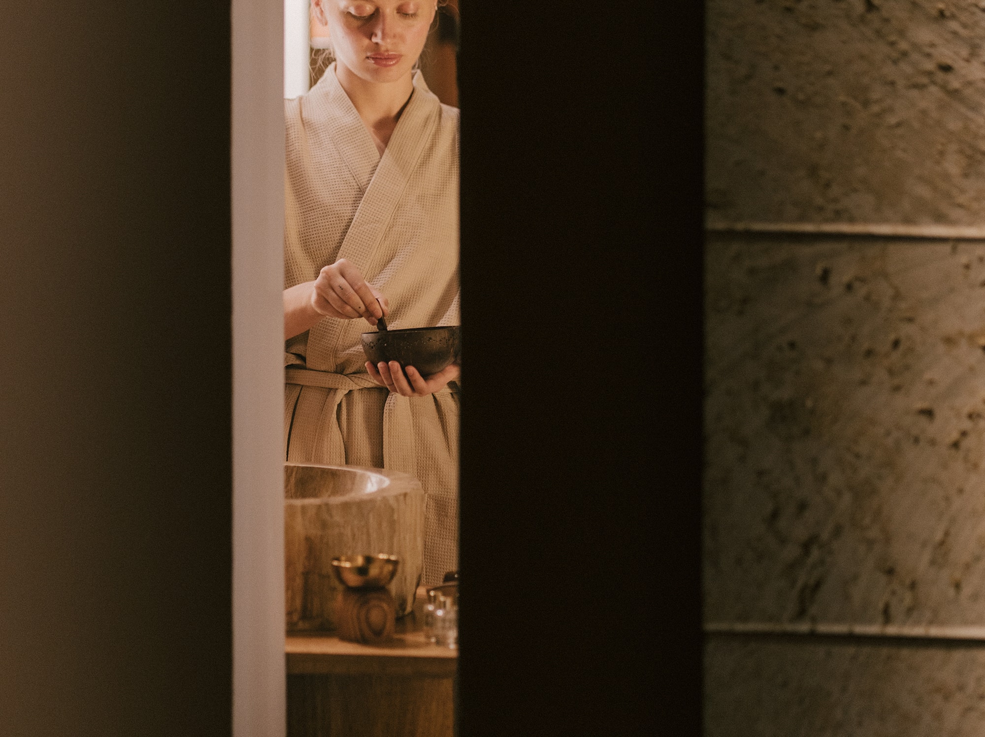 Mujer en albornoz, ojos cerrados, prepara ritual de bienestar en spa.