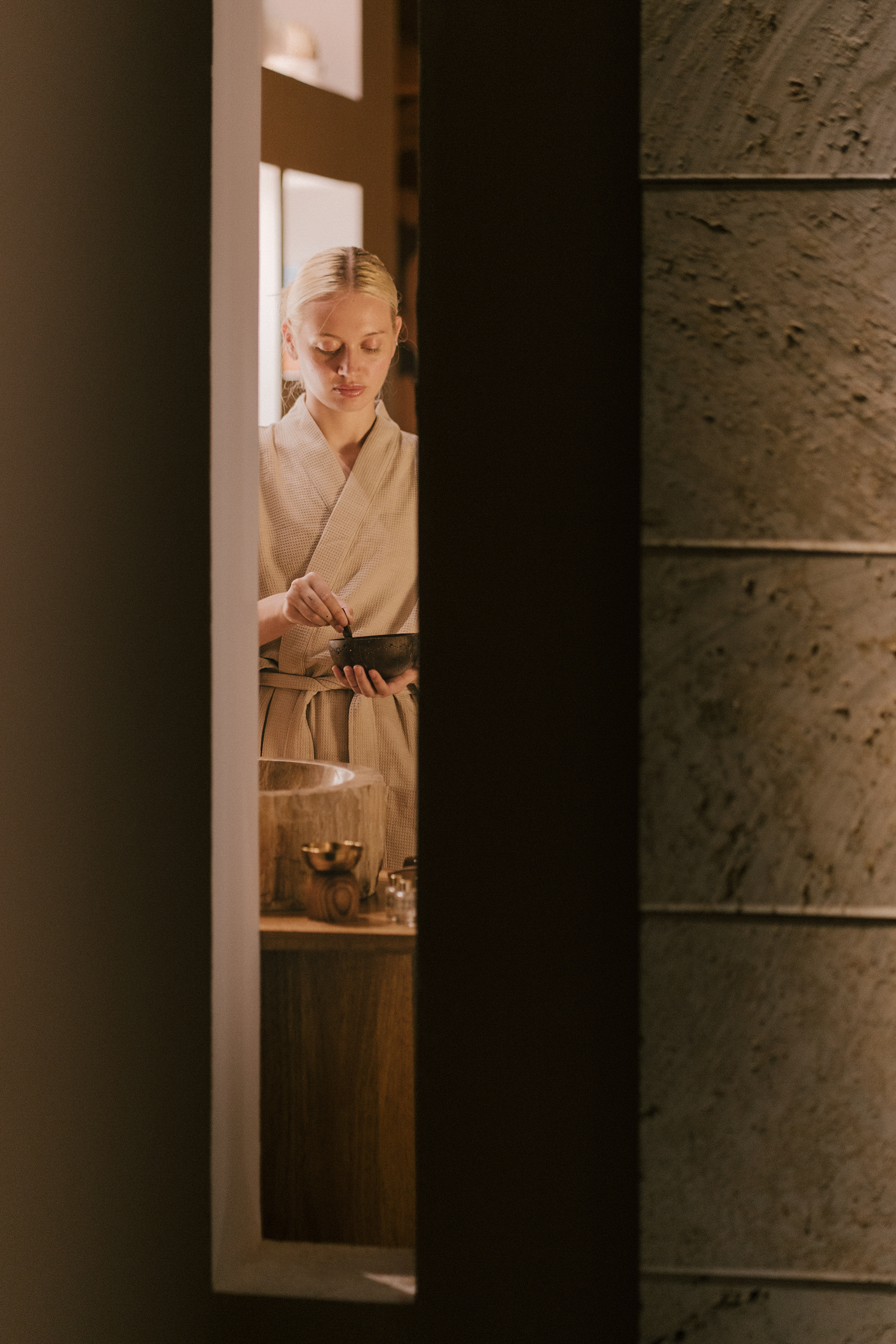Mujer en albornoz, ojos cerrados, prepara ritual de bienestar en spa.