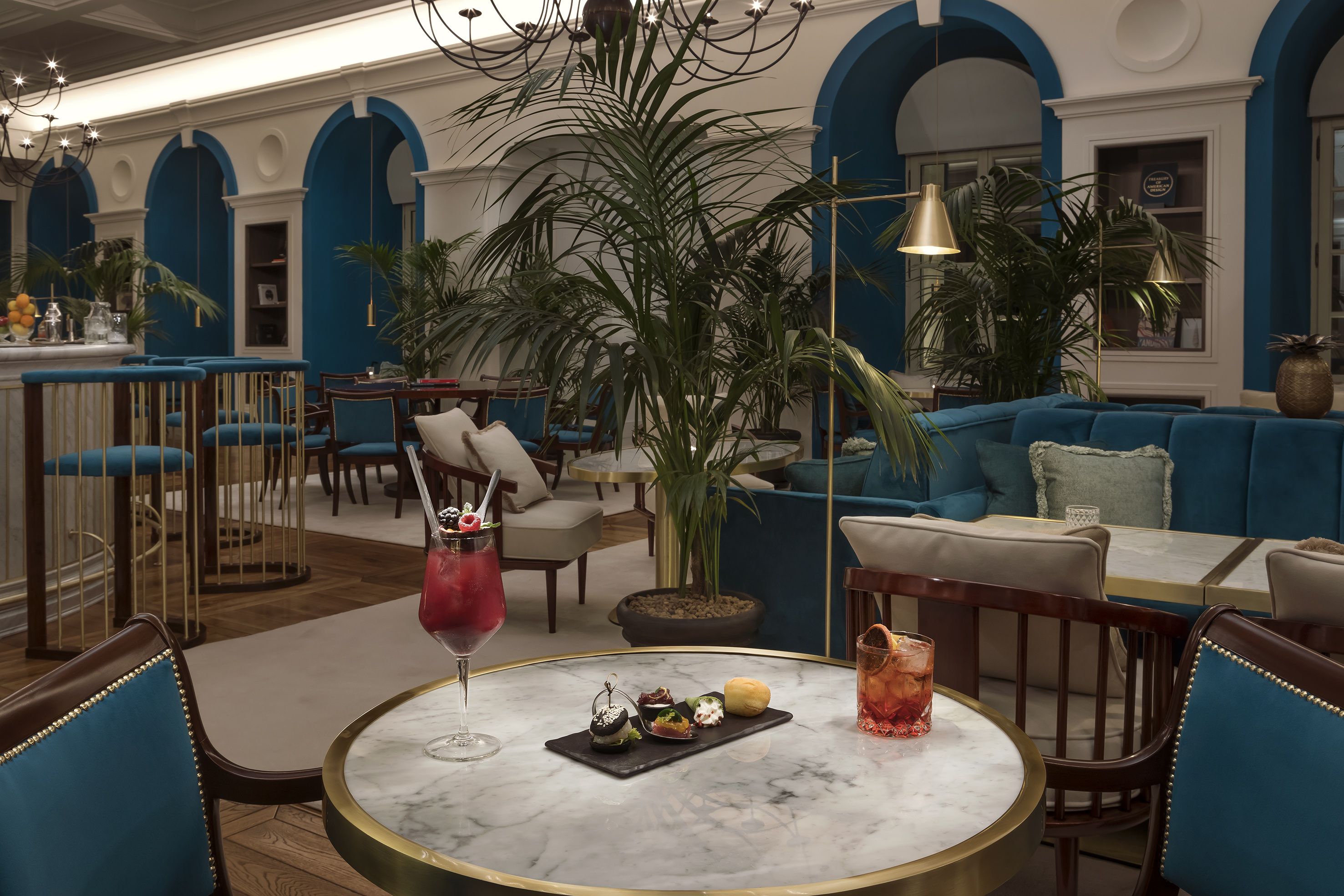 Elegant bar lounge with teal decor, marble tables, and refreshing cocktails.