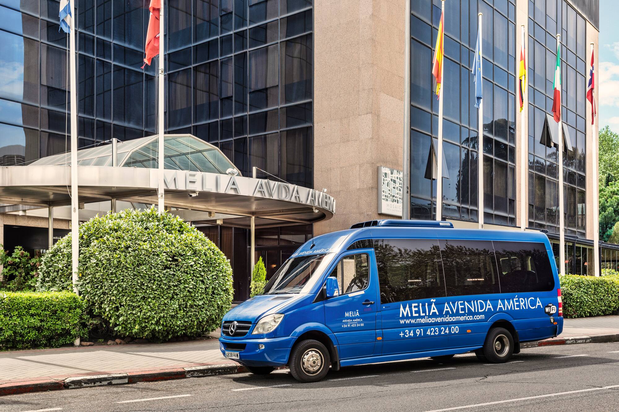 Melia Avenida America hotel exterior with blue shuttle van.
