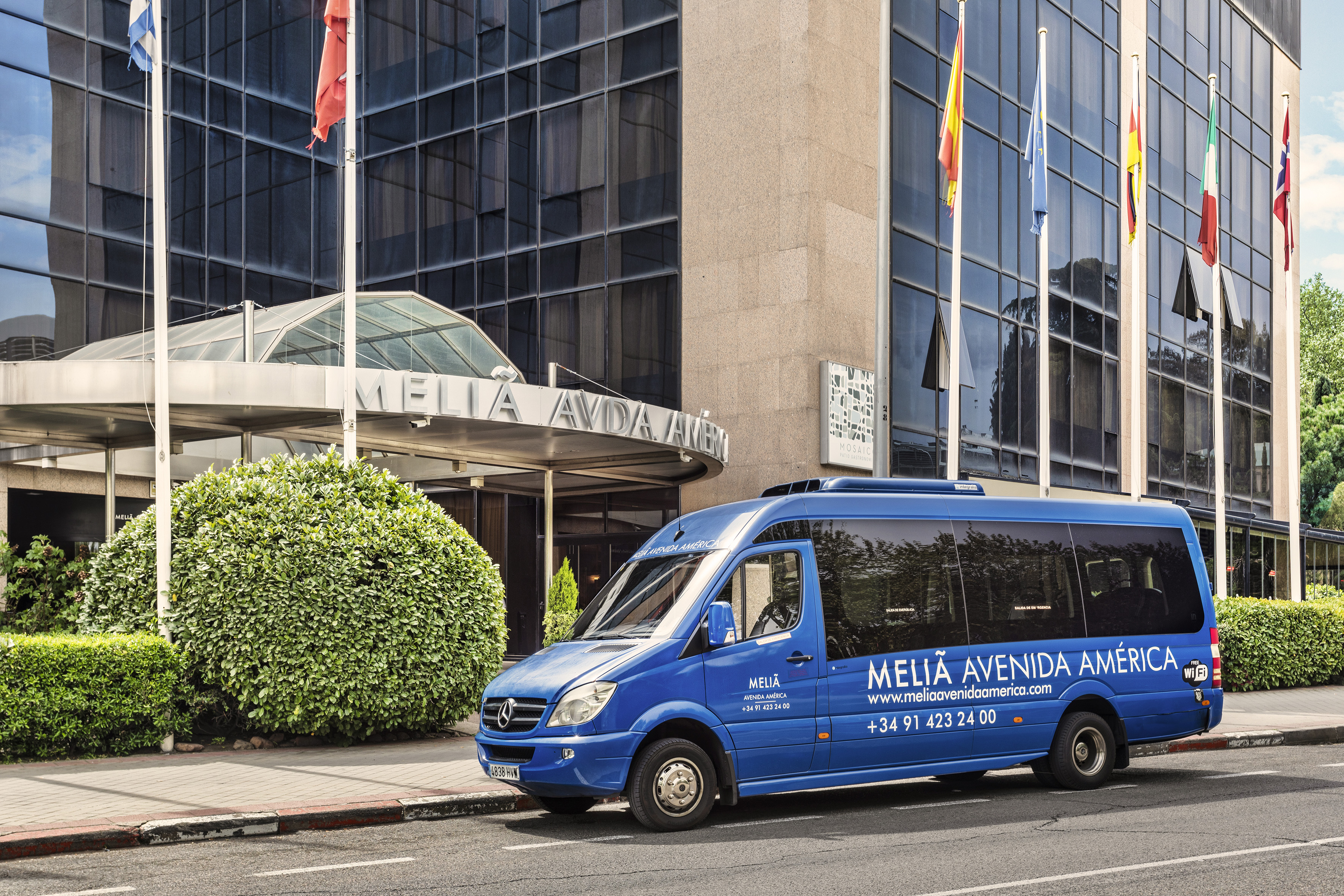 Melia Avenida America hotel exterior with blue shuttle van.