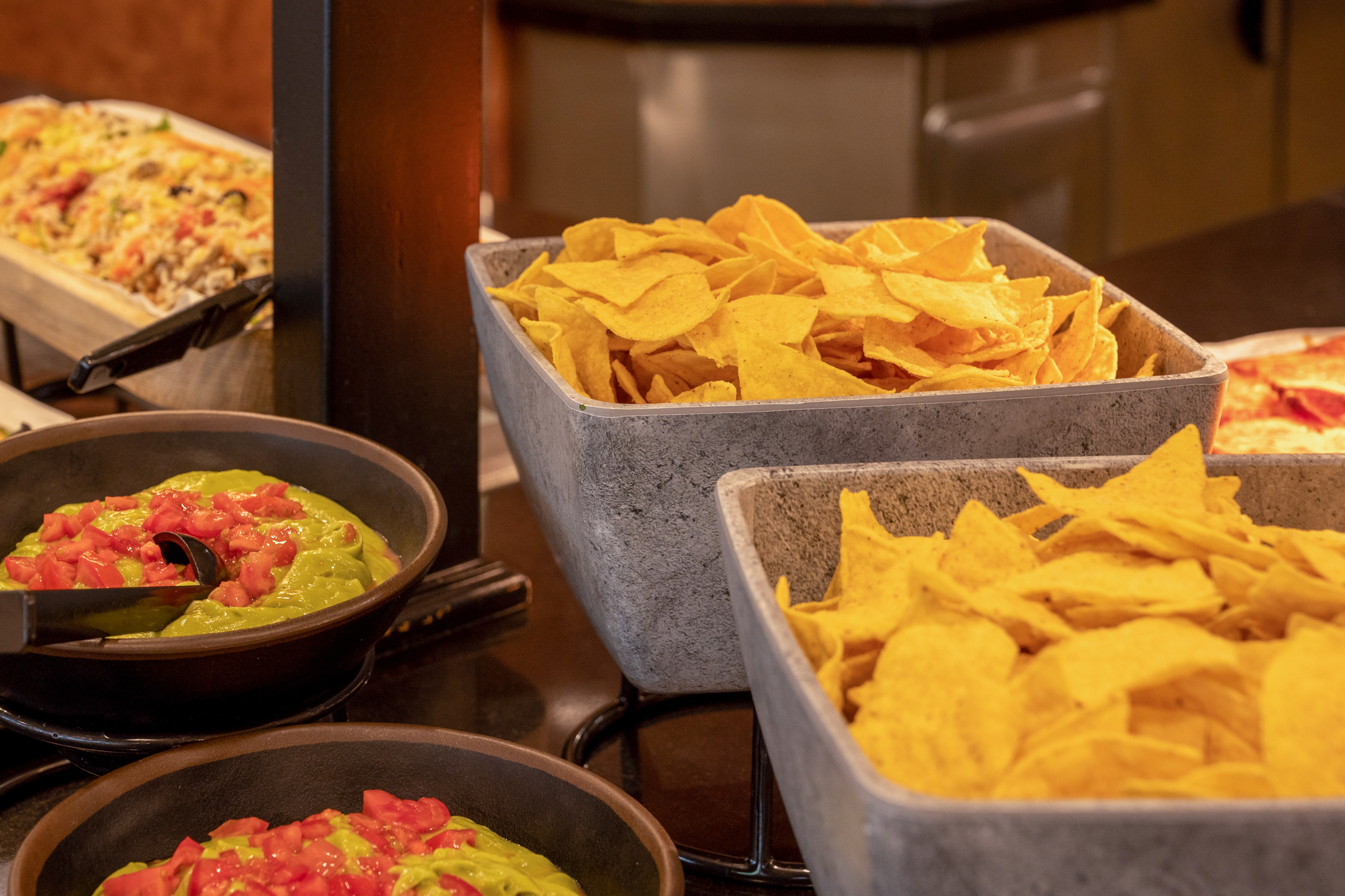 Nacho bar with golden corn tortilla chips and fresh guacamole with tomatoes.