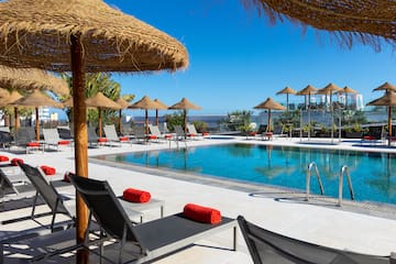 a pool with straw umbrellas and lounge chairs