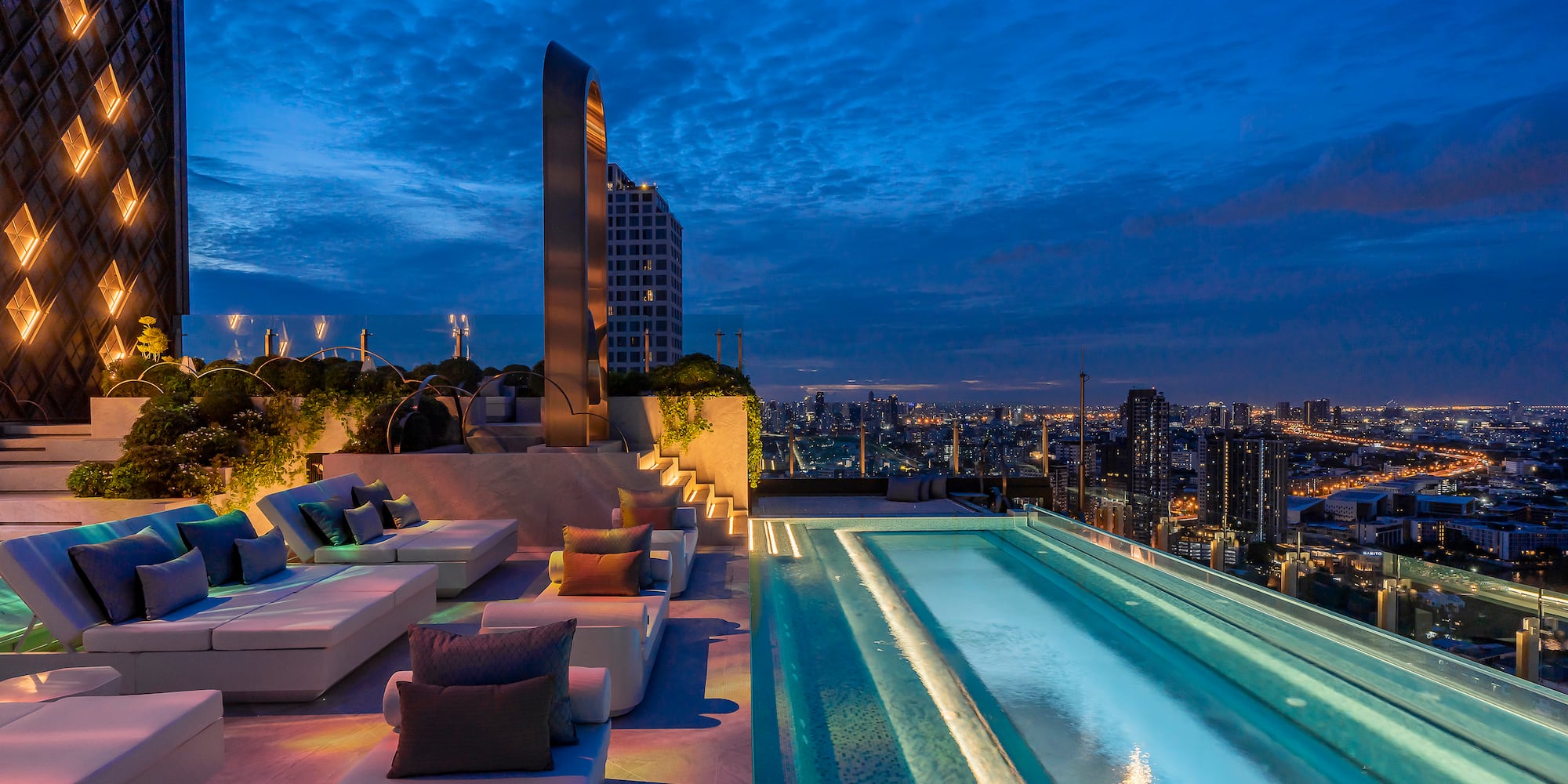 a rooftop pool with a large pool and a city skyline at night