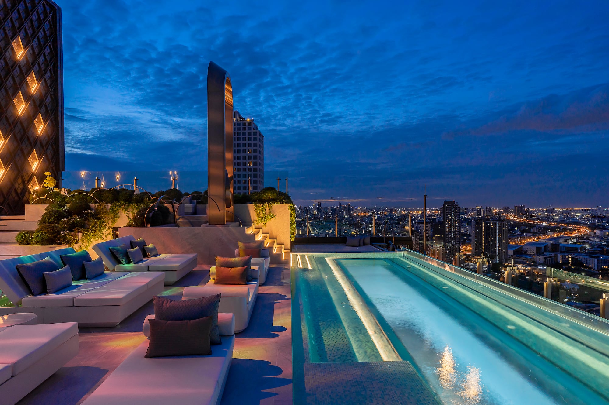 a rooftop pool with a large pool and a city skyline at night