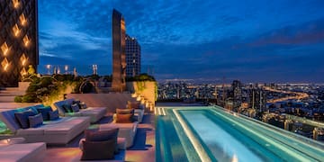 a rooftop pool with a large pool and a city skyline at night