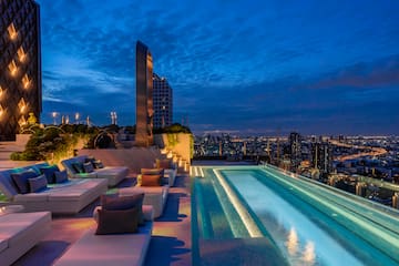 a rooftop pool with a large pool and a city skyline at night