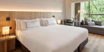 a bed with white sheets and a wood headboard in a hotel room