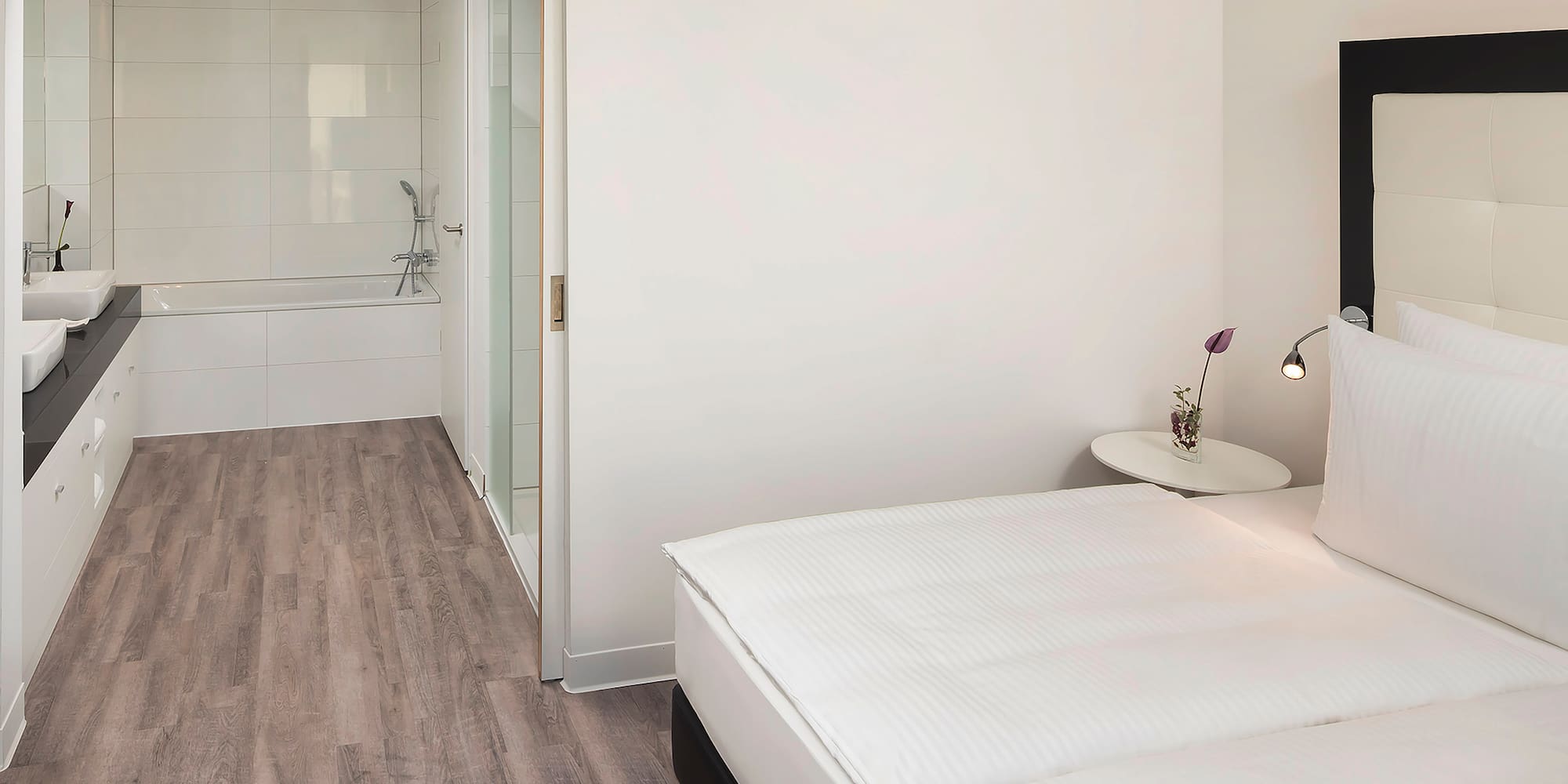 a bedroom with a white bed and a bathtub