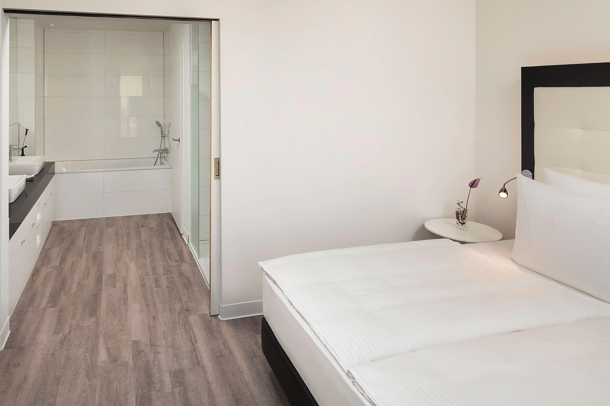 a bedroom with a white bed and a bathtub