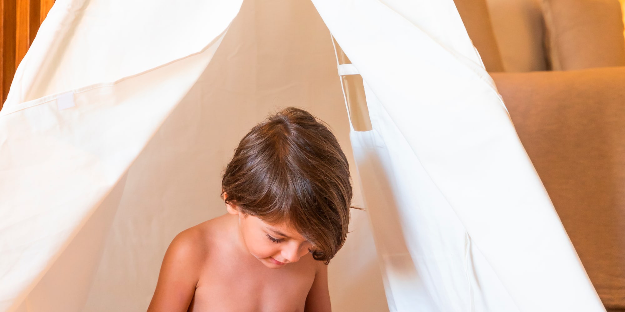 a child reading a book in a teepee