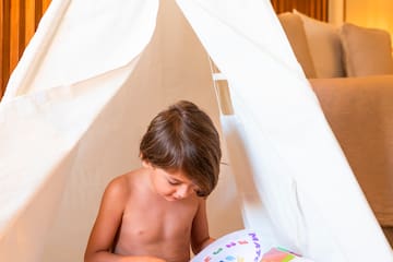 a child reading a book in a teepee