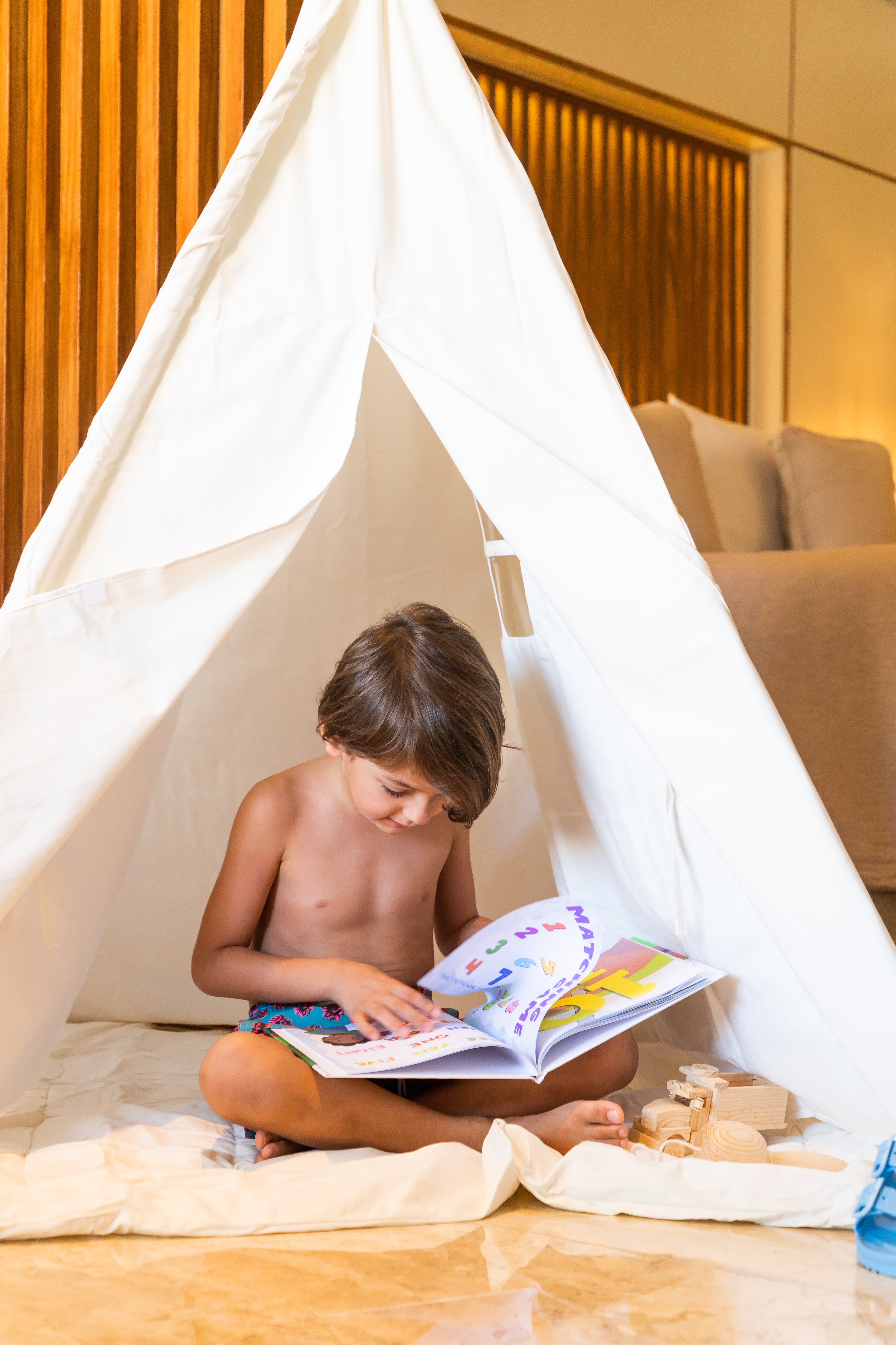 a child reading a book in a teepee