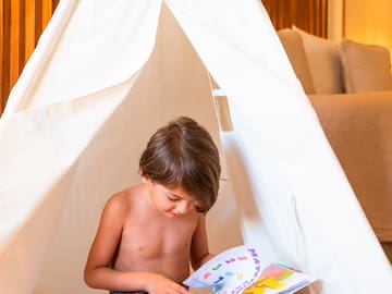 a child reading a book in a teepee