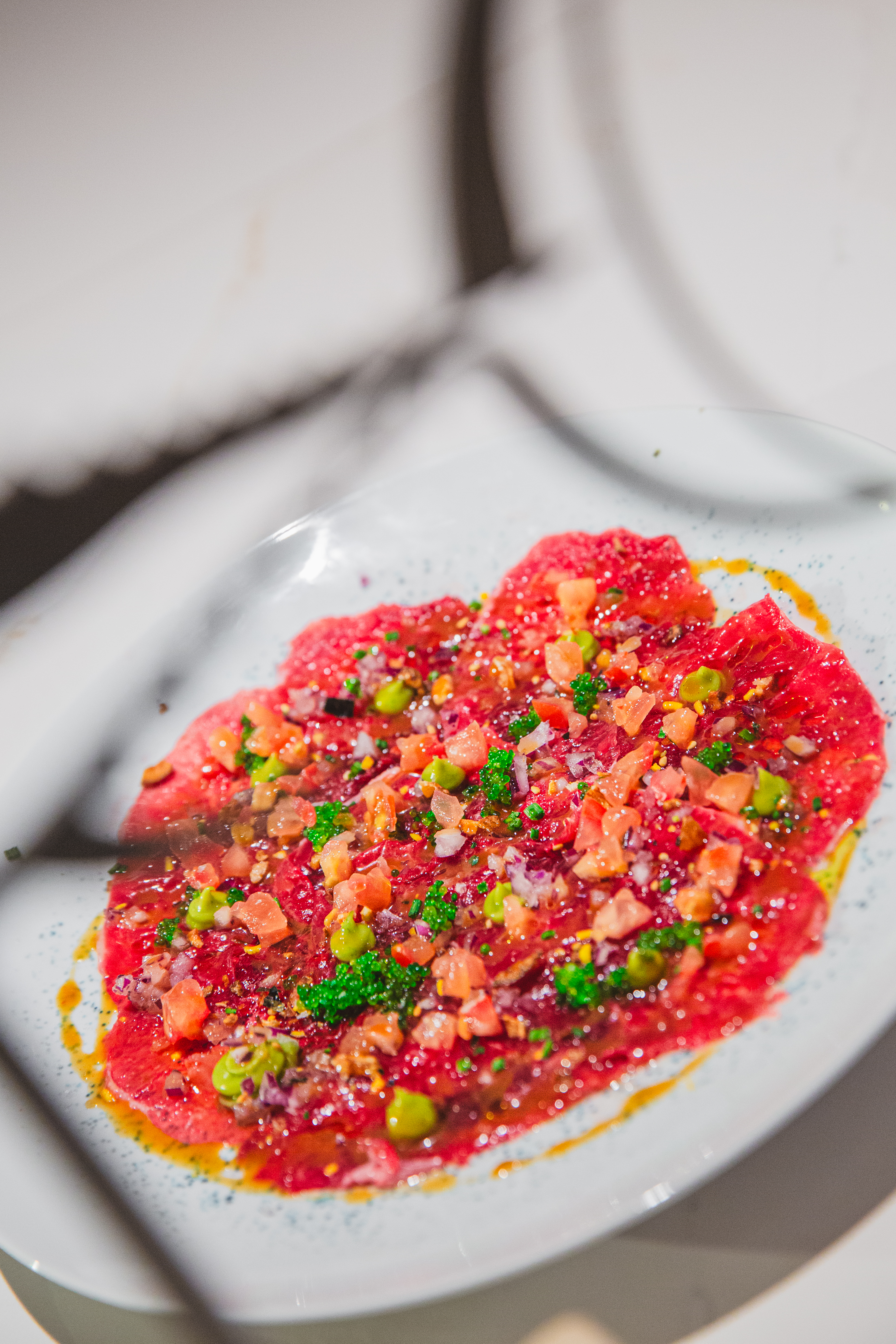 Fresh tuna carpaccio with diced tomatoes, green peas, red onion, and citrus dressing.