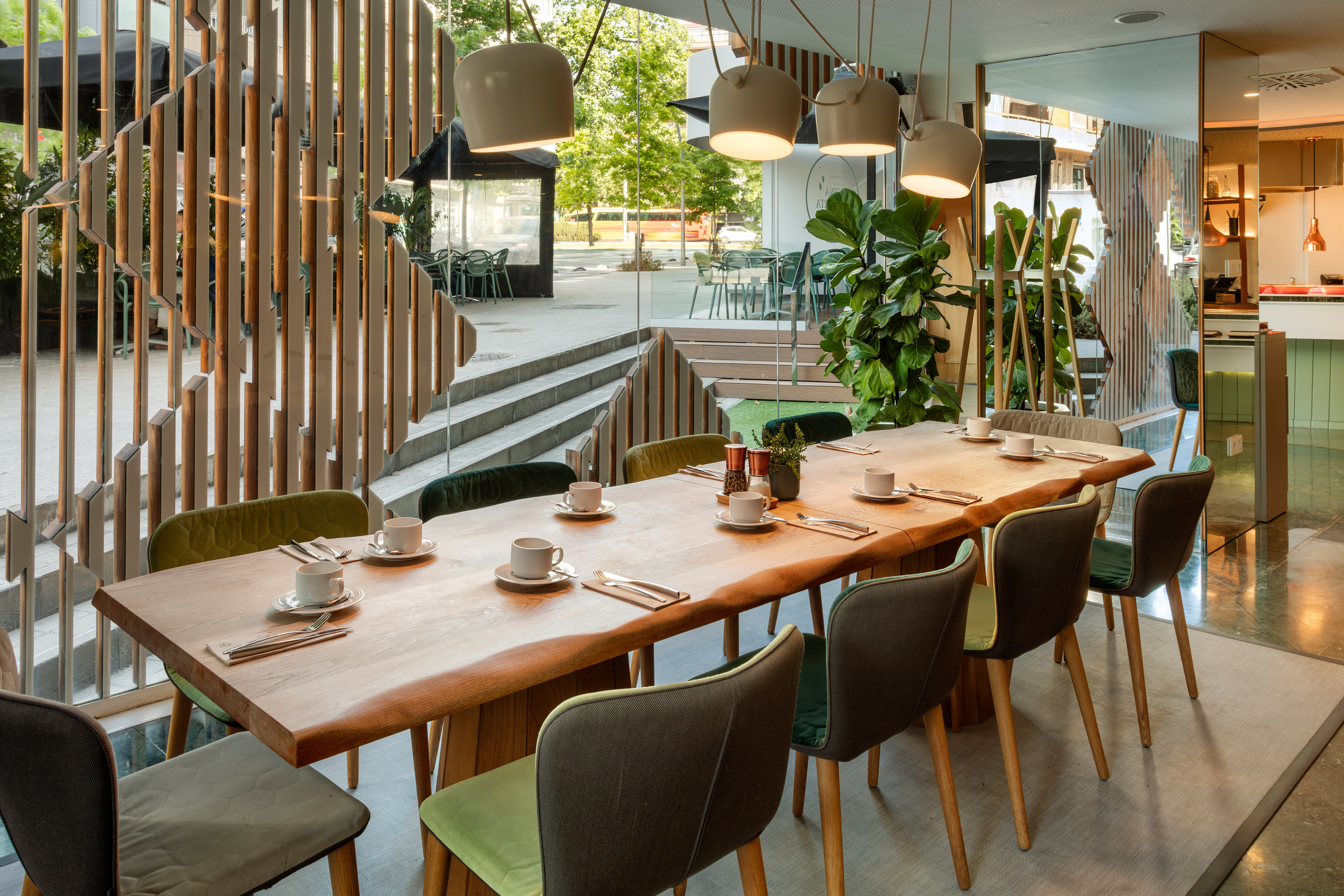Modern restaurant dining table, green chairs, bright space with outdoor view.