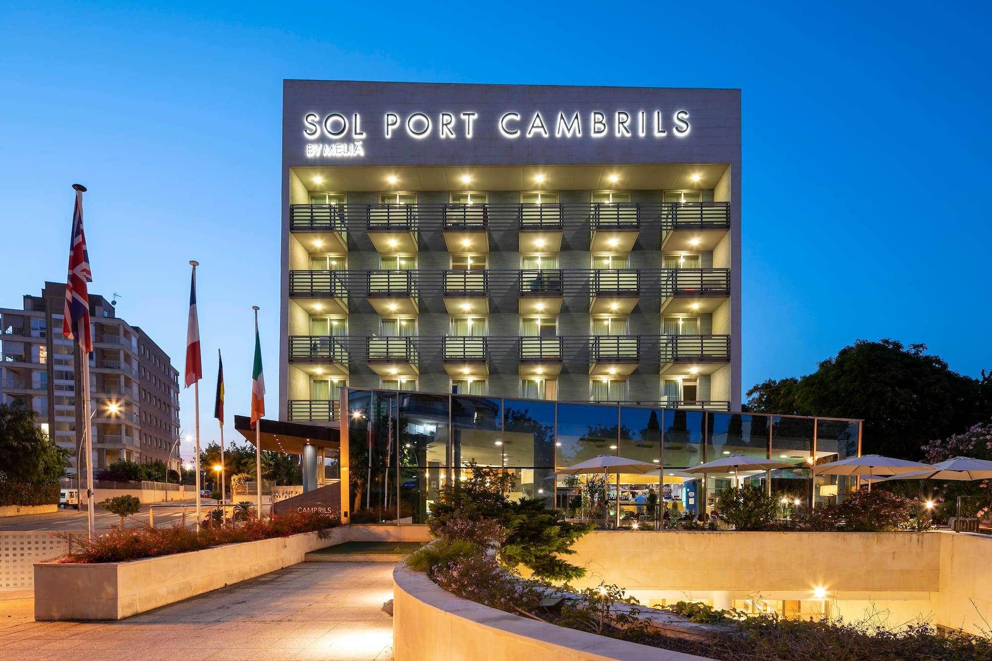 Sol Port Cambrils Meliá hotel exterior at dusk, with illuminated sign and balconies.