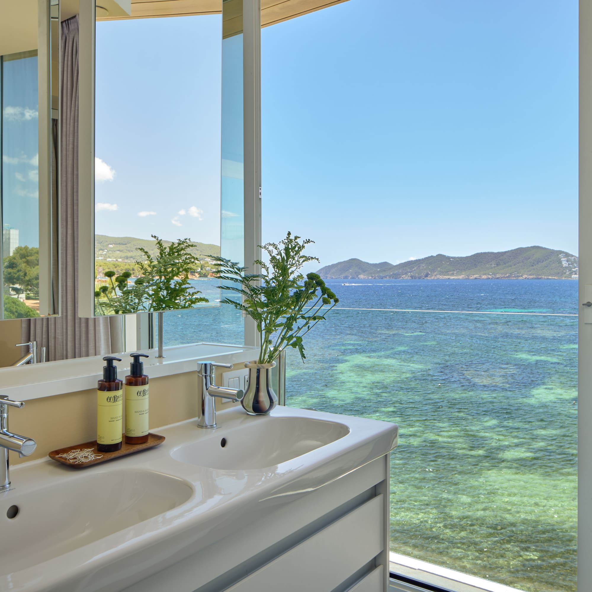 Luxury bathroom with double sinks overlooking the clear blue sea.