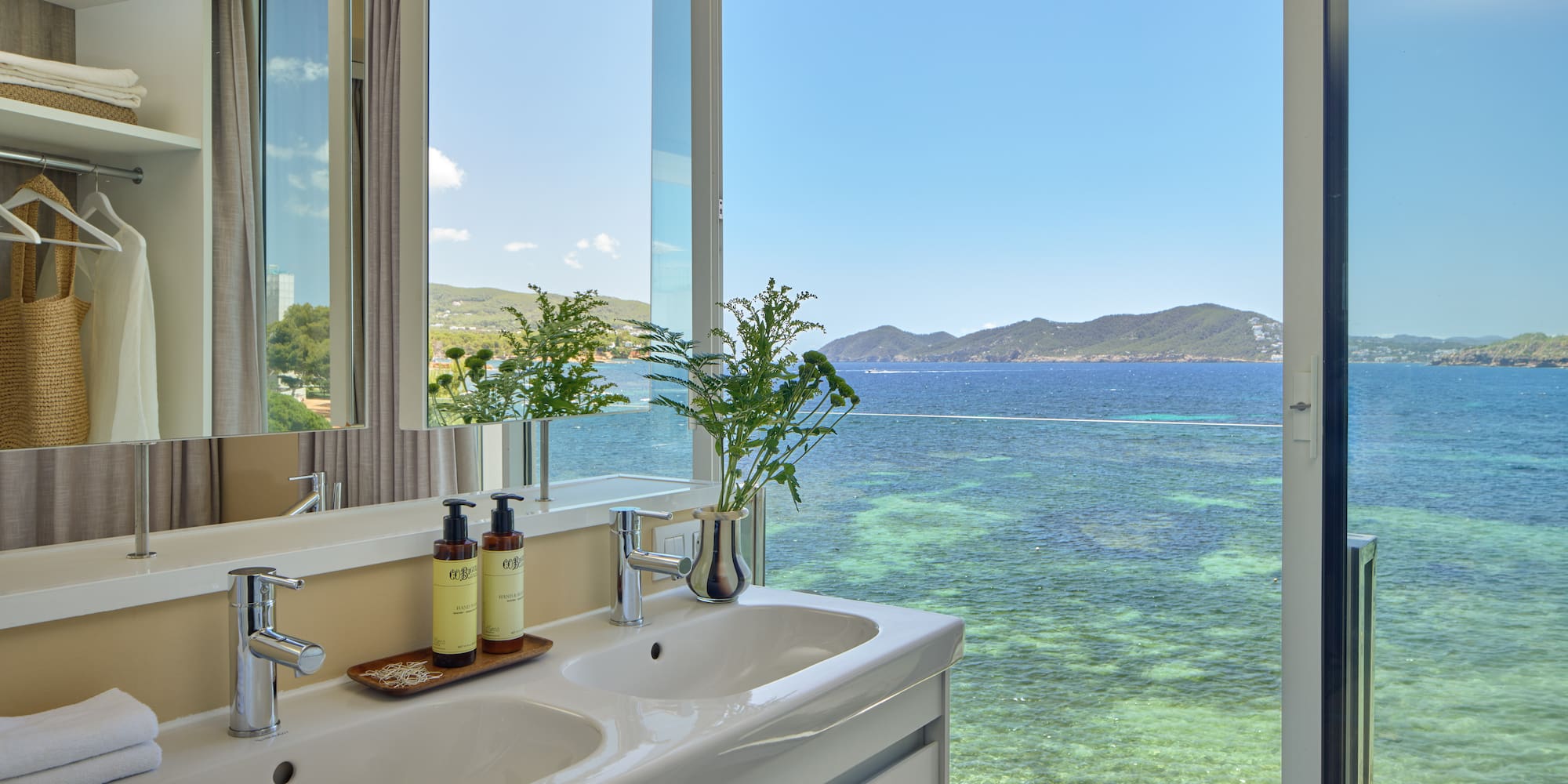 Luxury bathroom with double sinks overlooking the clear blue sea.
