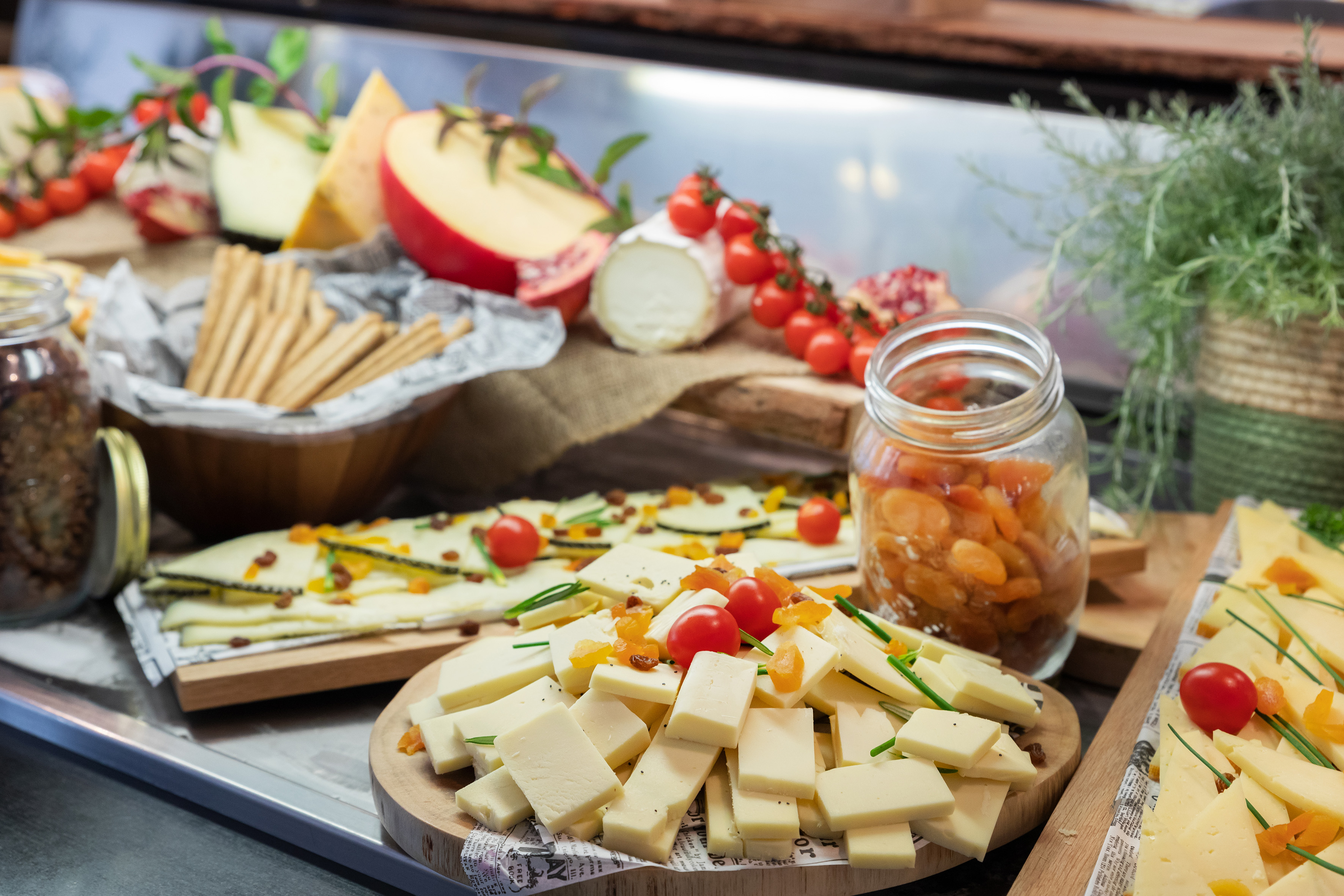 Cheese buffet featuring sliced cheeses, cherry tomatoes, dried fruit, and crackers.