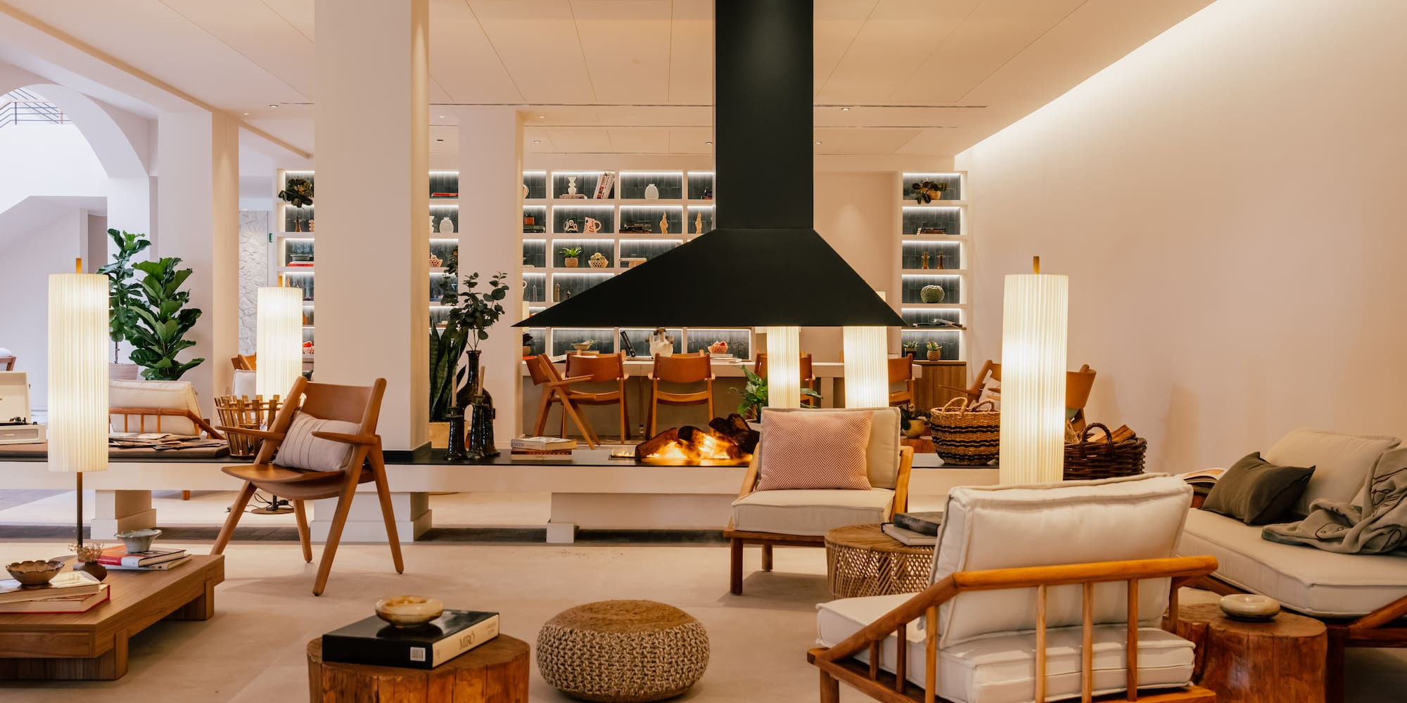 Stylish modern lounge interior with a central fireplace and wooden furnishings.