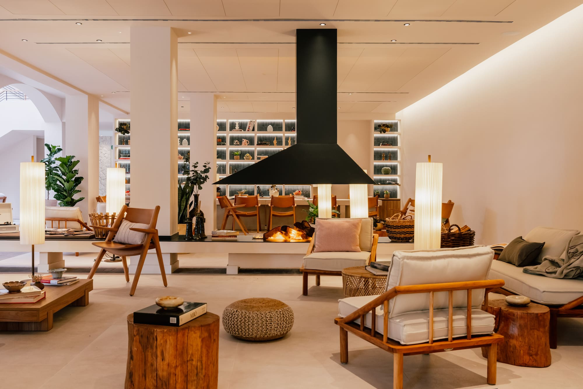 Stylish modern lounge interior with a central fireplace and wooden furnishings.