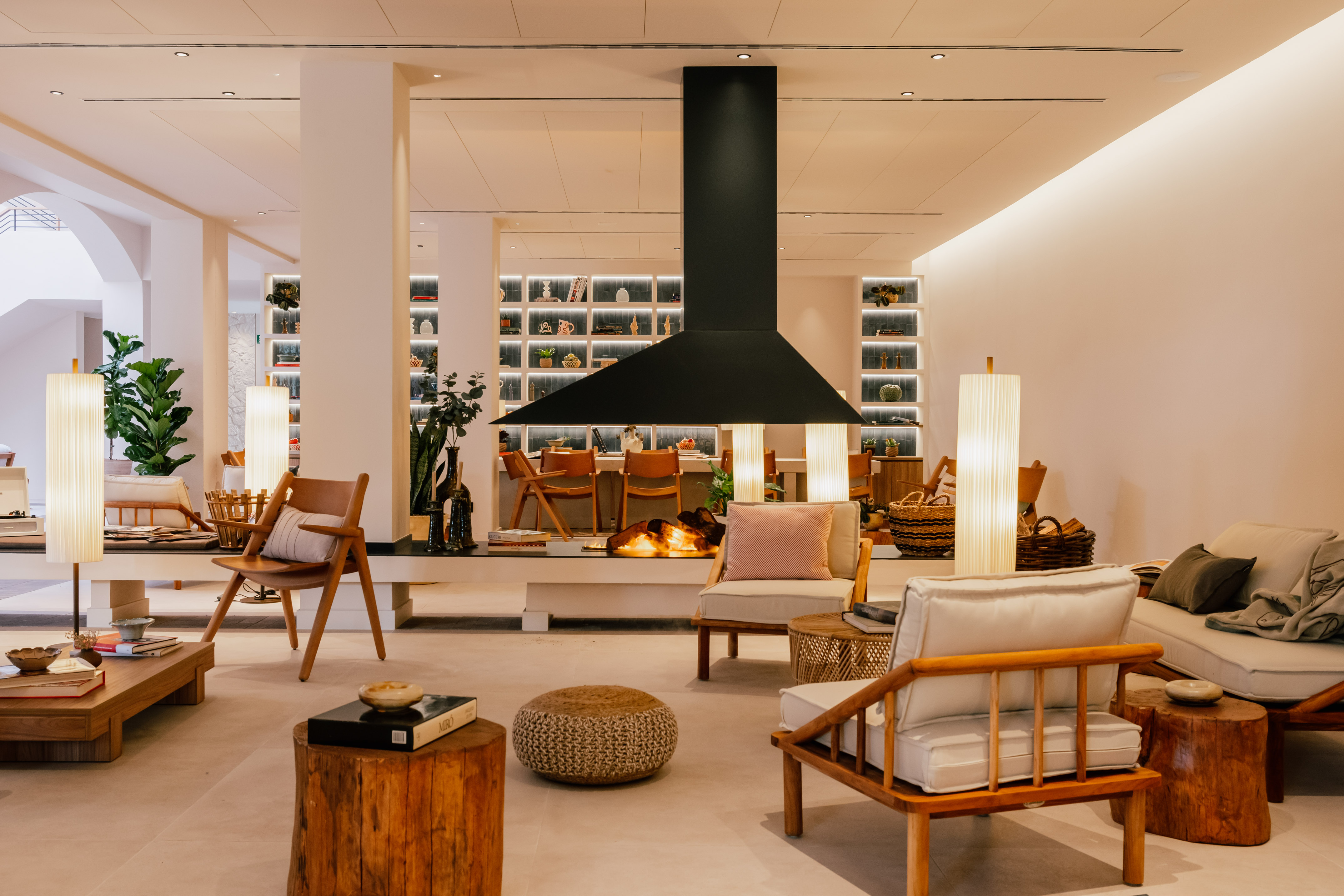 Stylish modern lounge interior with a central fireplace and wooden furnishings.