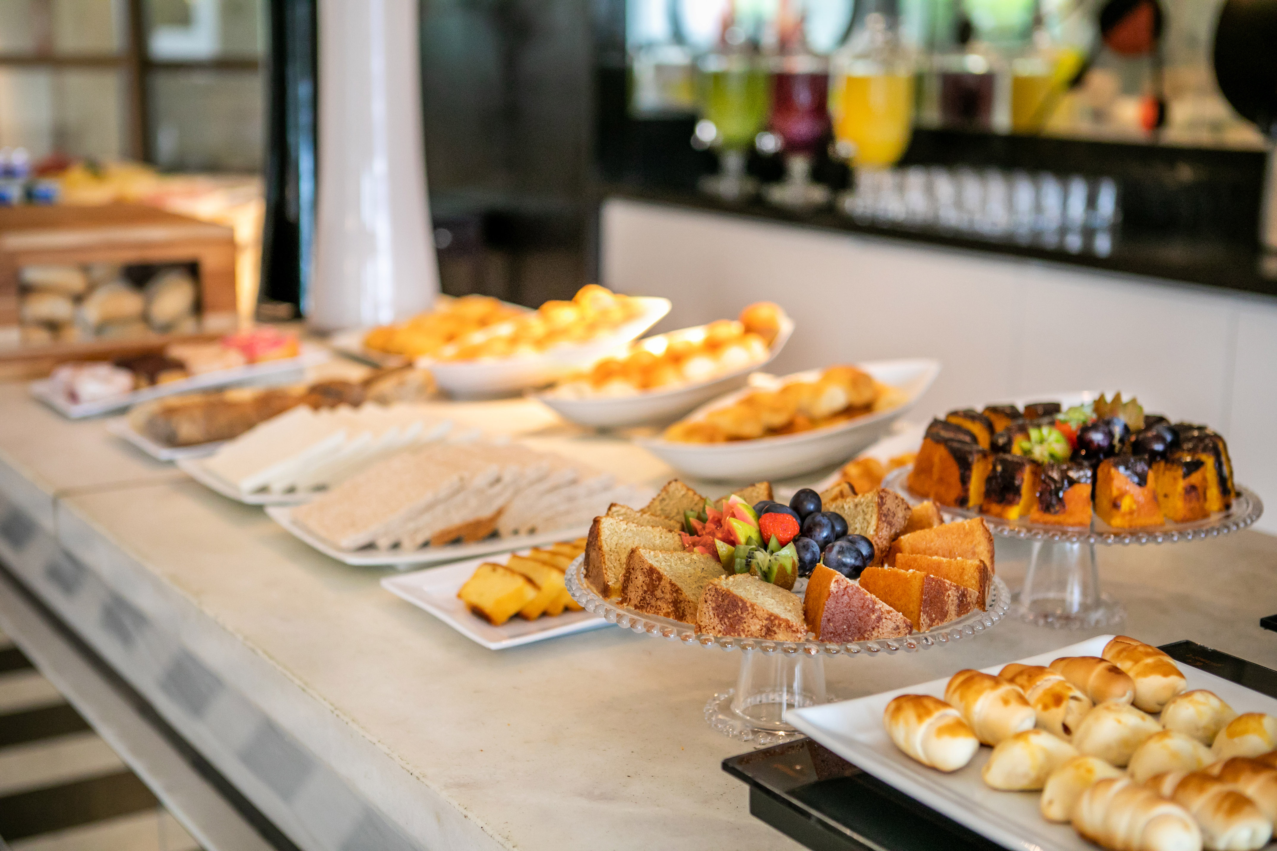 Hotel breakfast buffet featuring cakes, pastries, sandwiches, and fresh fruit.