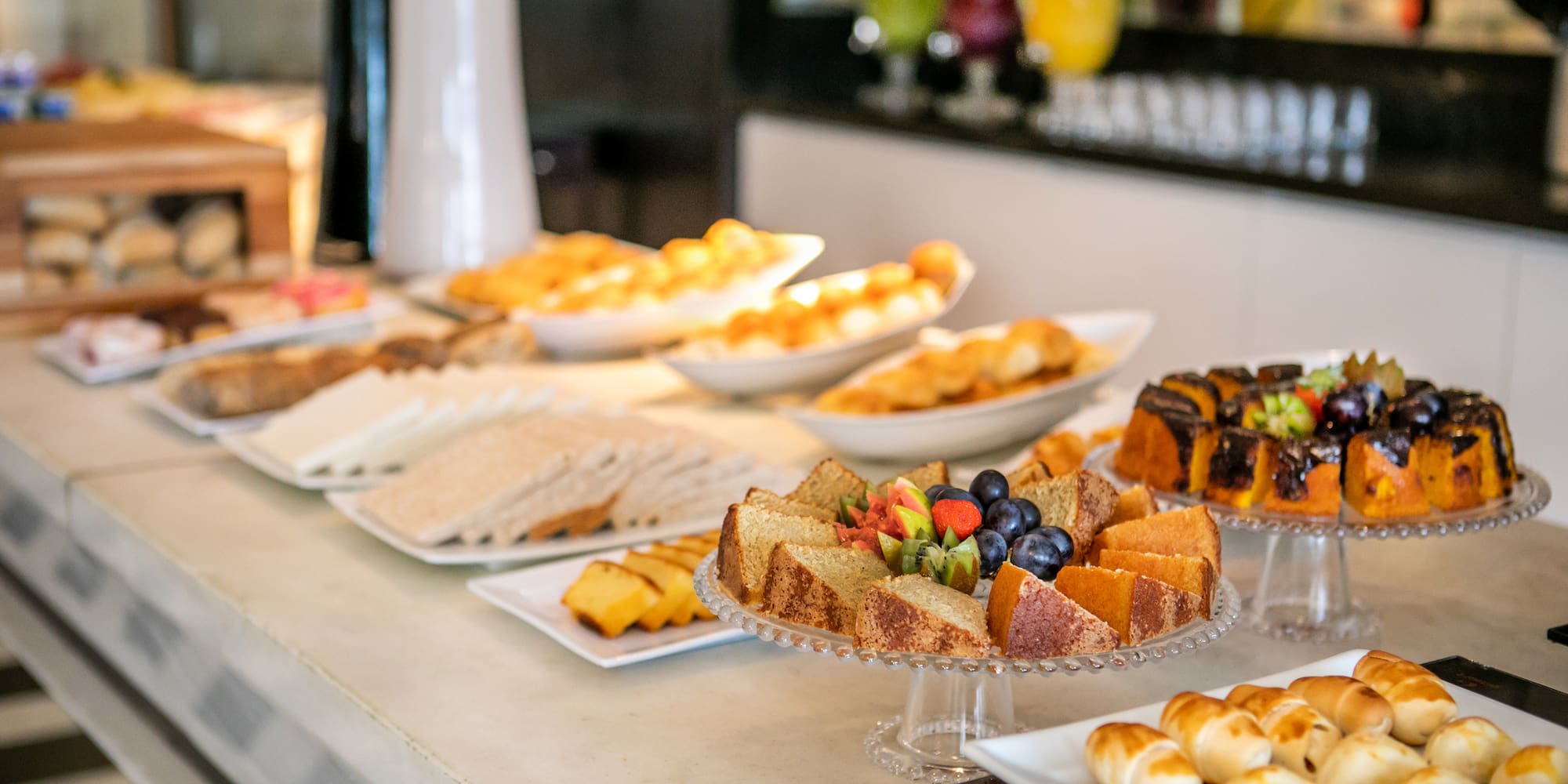 Hotel breakfast buffet featuring cakes, pastries, sandwiches, and fresh fruit.